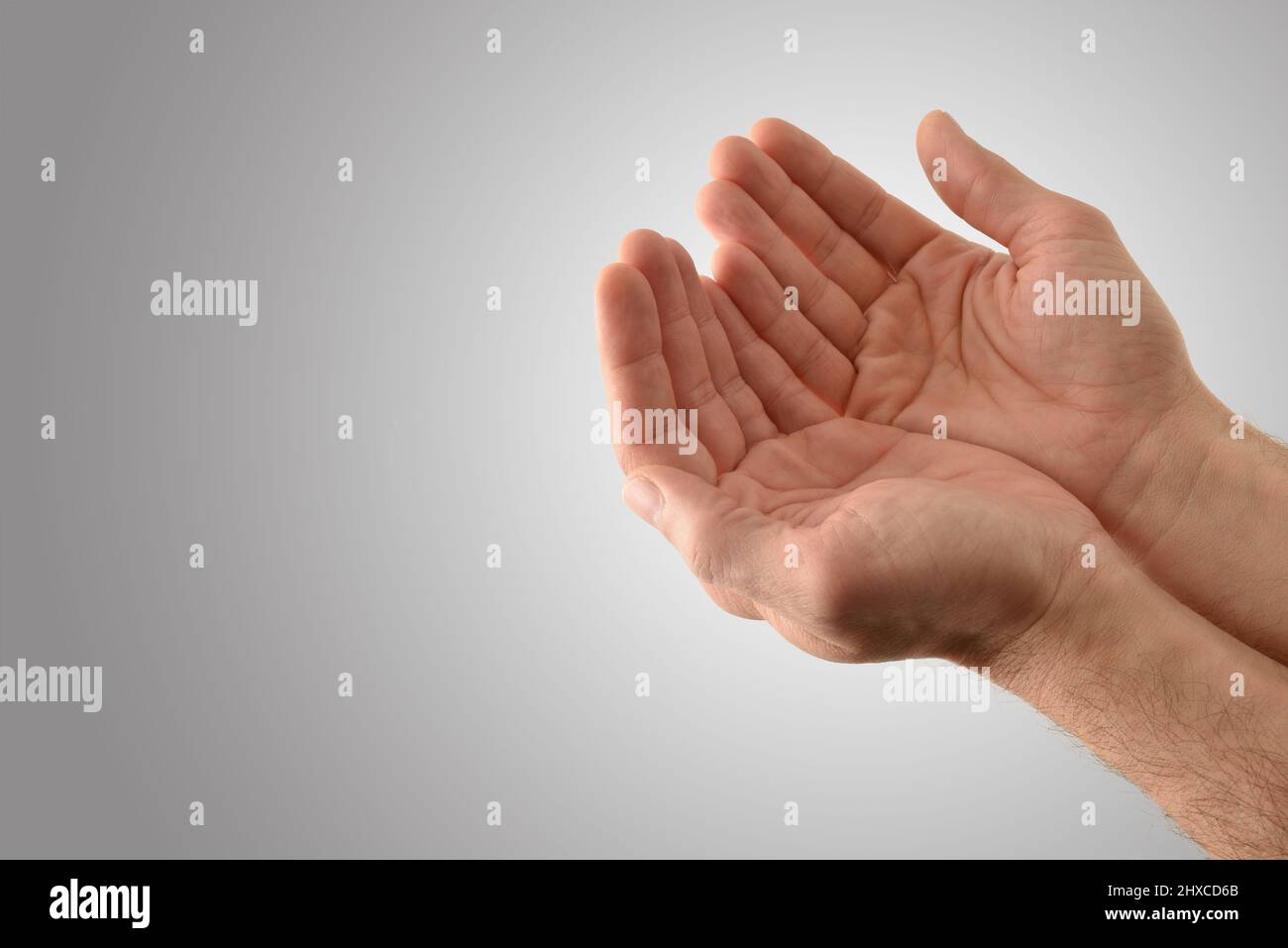 Hände mit Handflächen nach oben eines religiösen Mannes mit Offerfunktion auf isoliertem grauen Hintergrund. Erhöhte Ansicht. Stockfoto