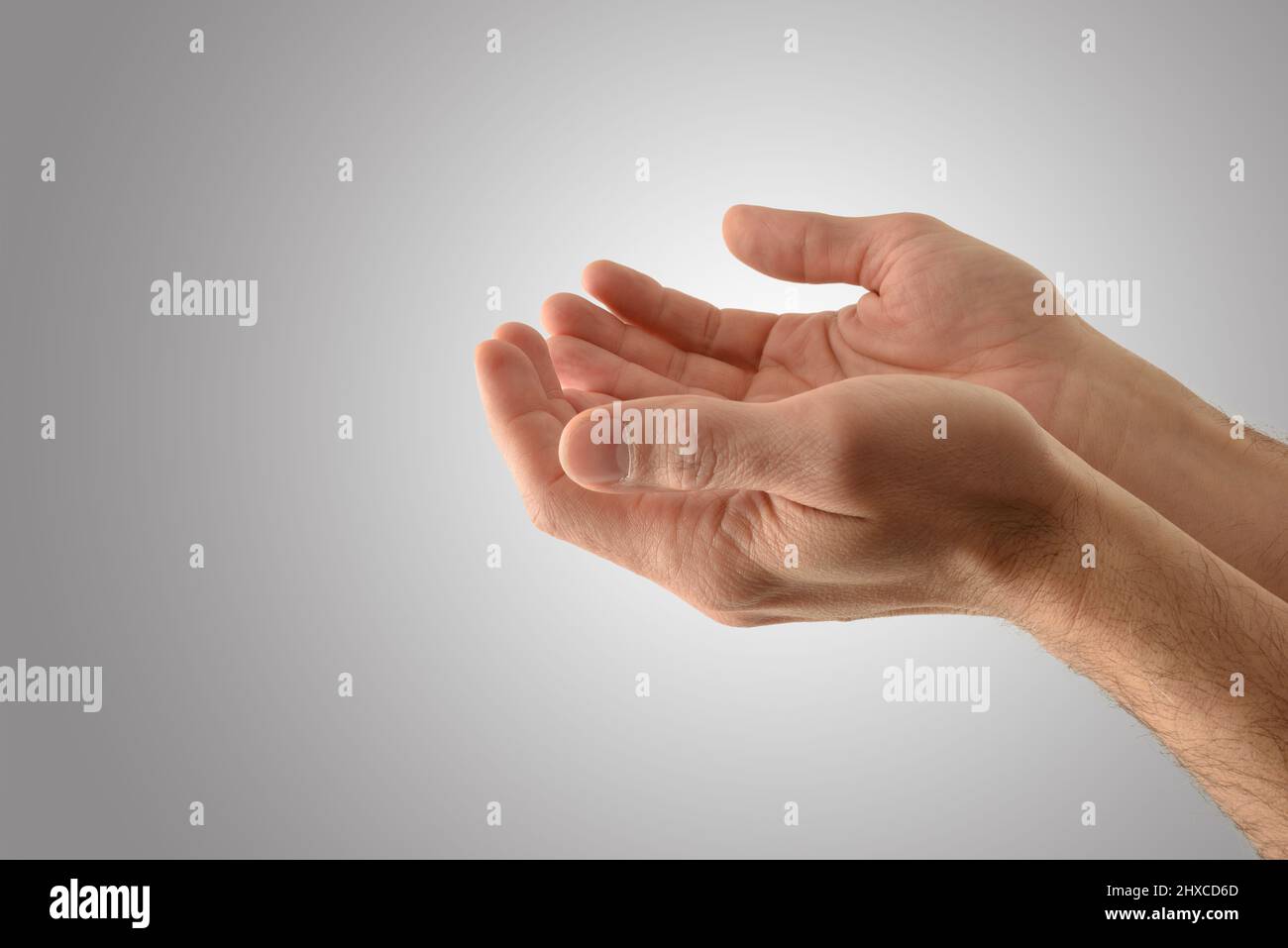 Detail Hände mit Handflächen nach oben von einem religiösen Mann mit bieten Geste mit isolierten grauen Hintergrund. Seitenansicht. Stockfoto