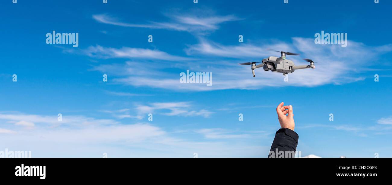 Drohne landet auf männlicher Hand vor blauem Himmel Hintergrund Stockfoto
