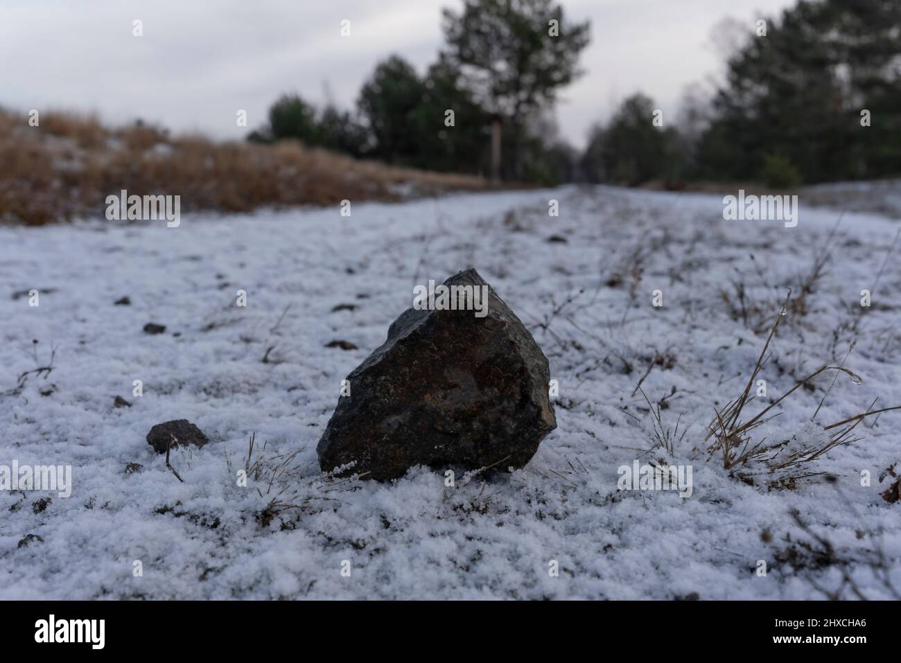 Auf einer leicht verschneiten Waldstraße liegt der Granitstein des Spitzers Stockfoto