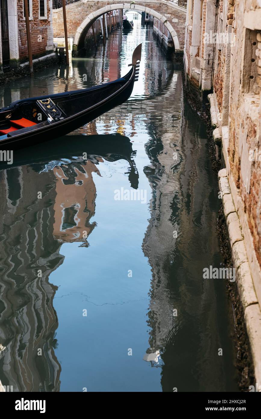 Prow einer venezianischen Gondel in einem kleinen Kanal mit den umliegenden Gebäuden im Wasser reflektiert Stockfoto
