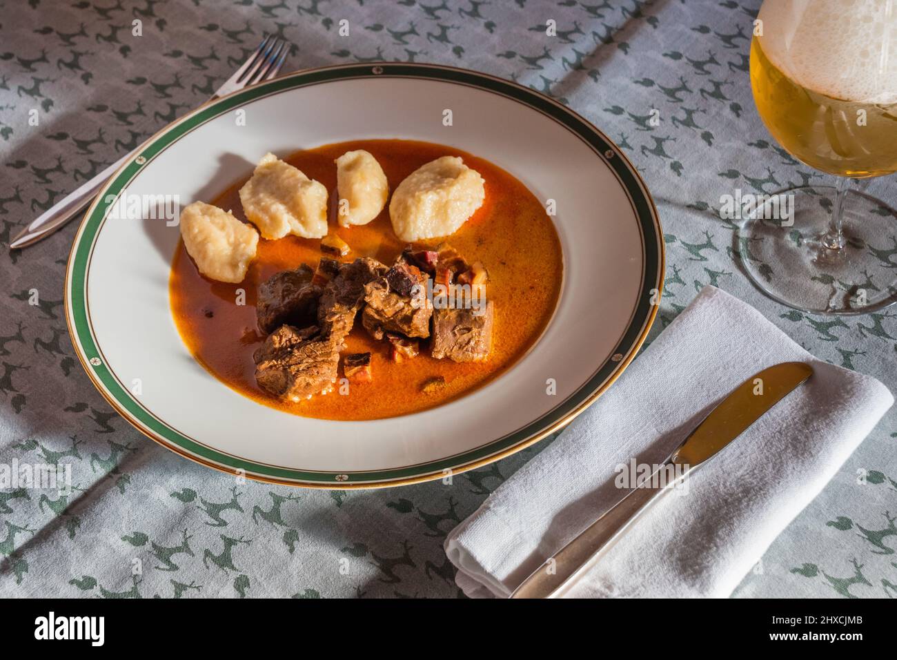 Wild Gulash Wild-Hotpot mit Knödeln mit Paprika-Soße und einem Glas Bier Stockfoto