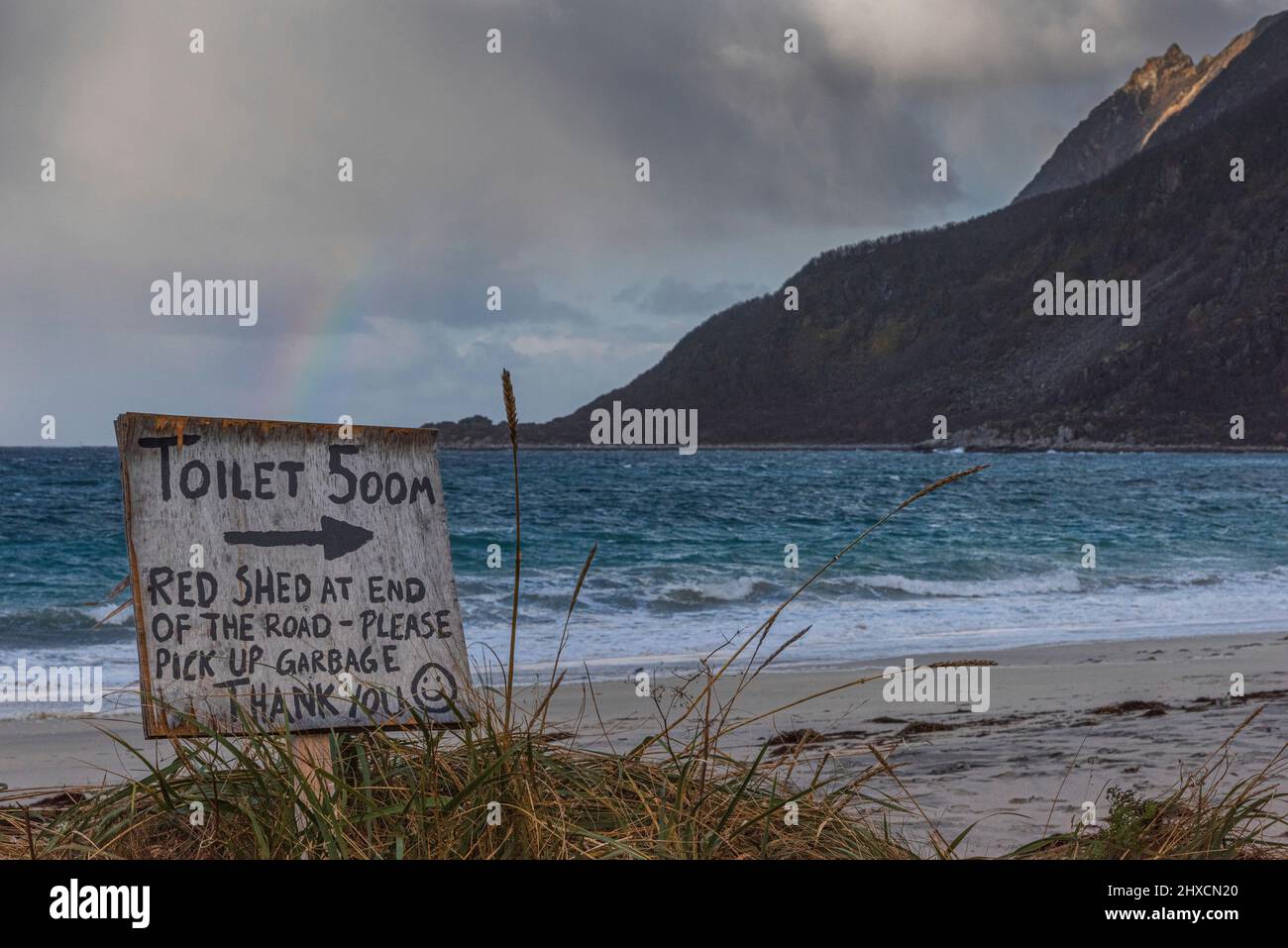 Herbstimpressionen von der norwegischen Insel Senja über dem Polarkreis, Skandinavien und Norwegen reiner Sandstrand bei Bovaer - Bovaer (Skaland) im Nordwesten der Insel, wo die Straße endet, Schild Toiletten 500 m, bitte Müll abholen, Regenbogen, Stockfoto