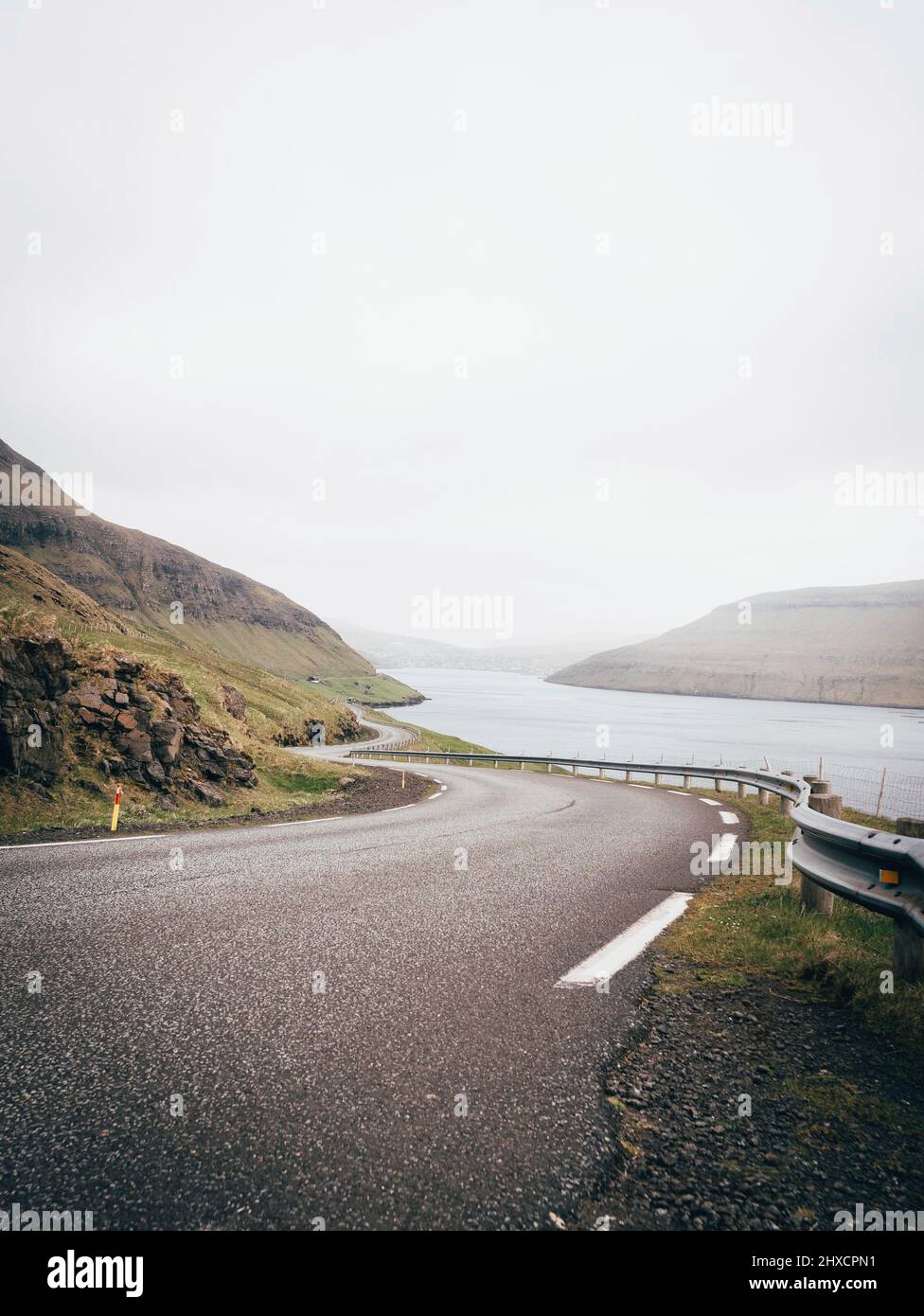 Weite, grüne Hügel auf den Färöer Inseln mit Straße Stockfoto