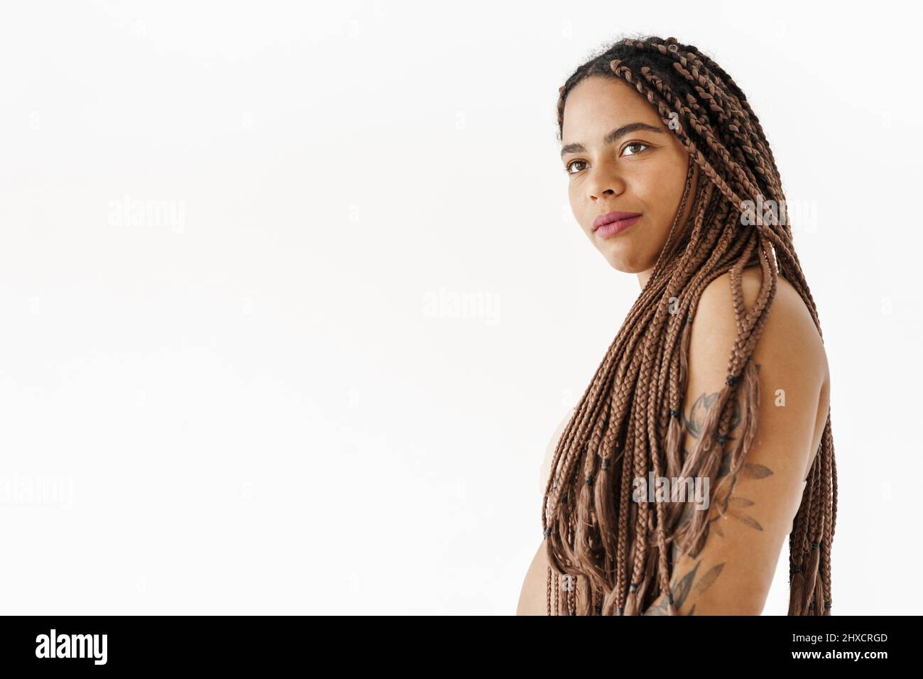 Lächelnde junge afrikanische Frau mit Dreadlocks über weißem Wandhintergrund Stockfoto