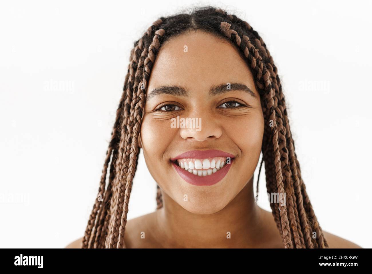 Lächelnde junge afrikanische Frau mit Dreadlocks über weißem Wandhintergrund und Blick auf die Kamera Stockfoto