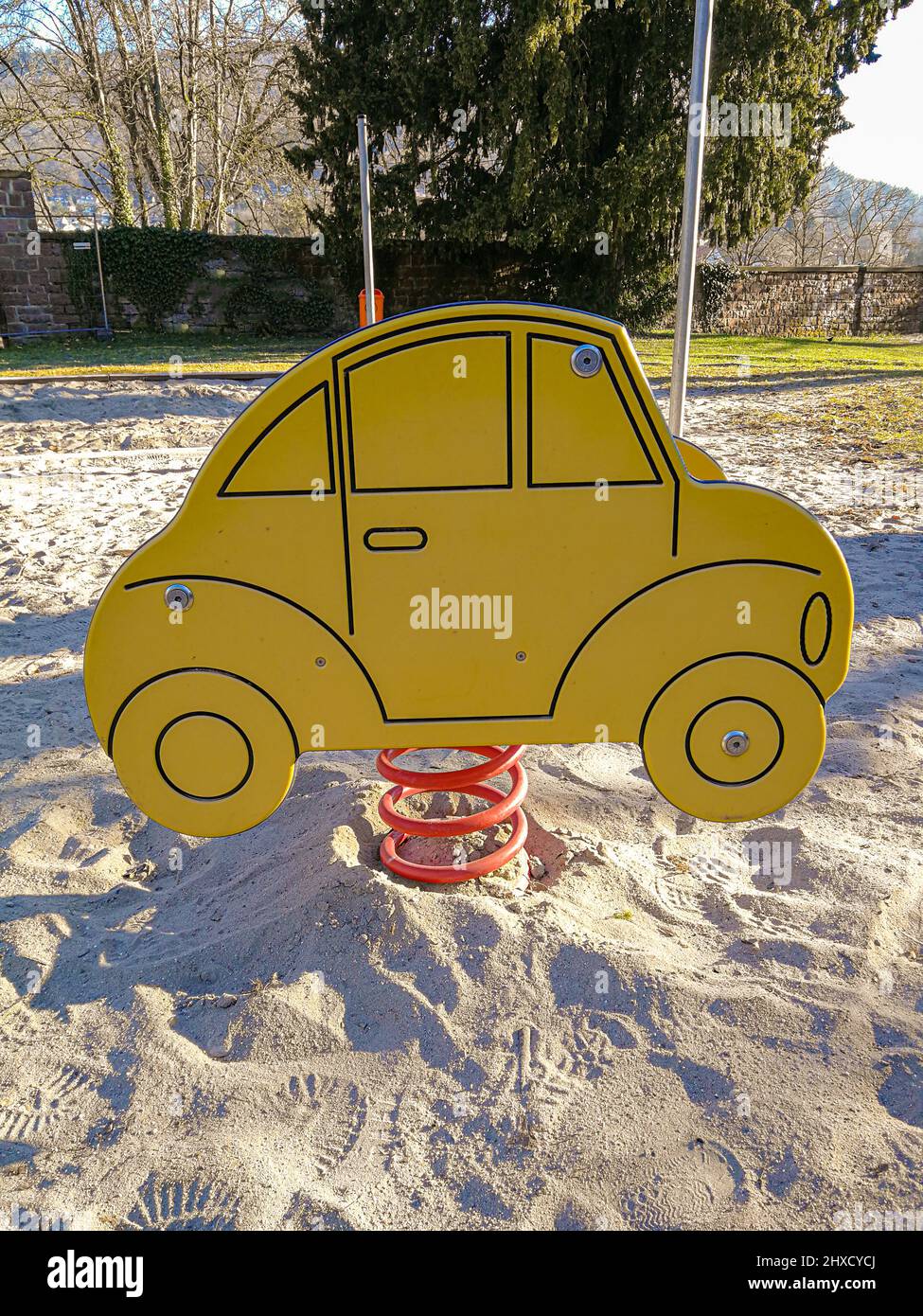 Frühling Wippe in Form eines stilisierten Autos auf einem leeren Kinderspielplatz mit Sandboden Stockfoto