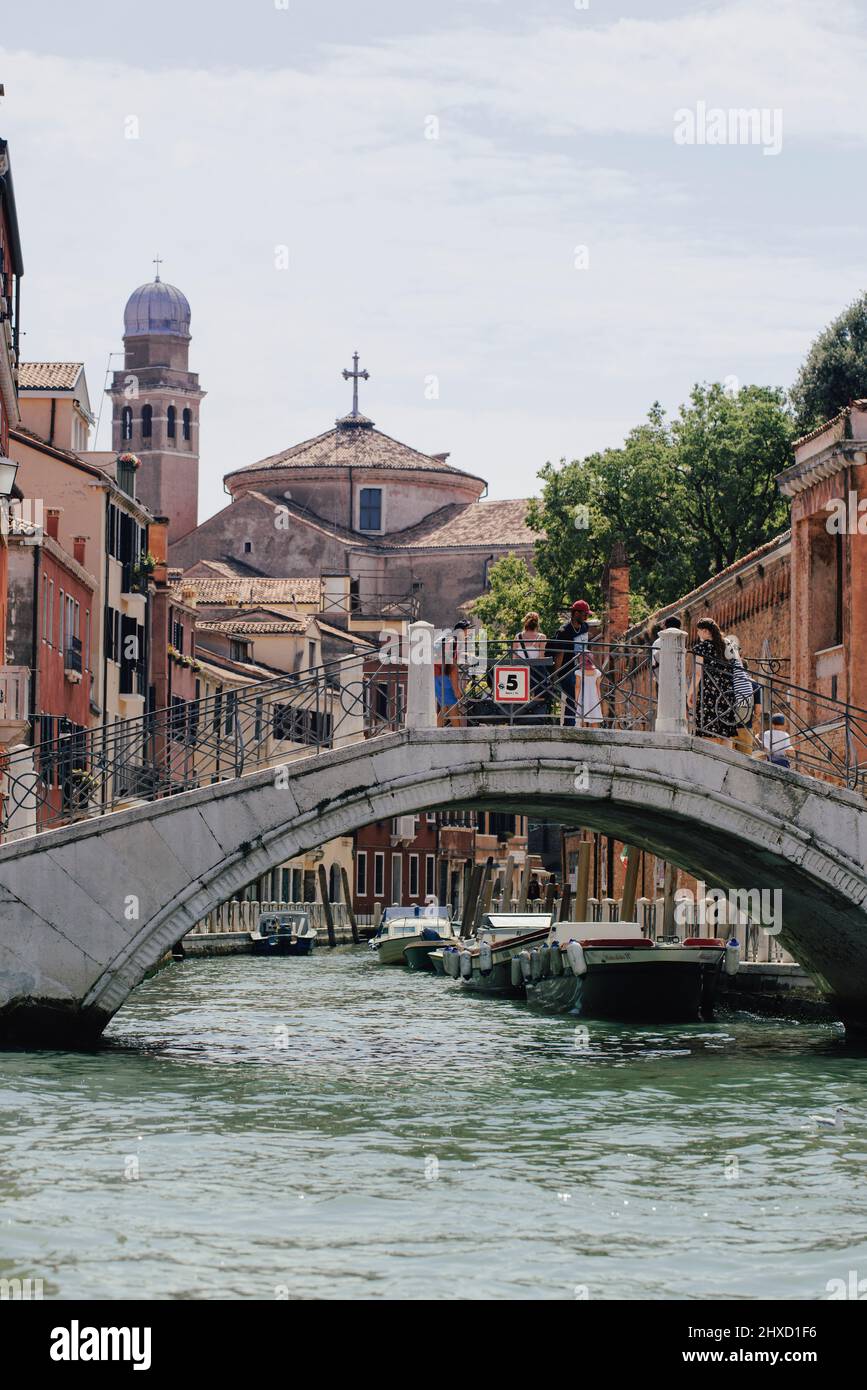 Kleiner Kanal mit venezianischer Brücke mit Blick auf die Chiesa di San Nicola da Tolentino und Giardini Papadopoli im Viertel Santa Croce in Venedig, Italien. Stockfoto