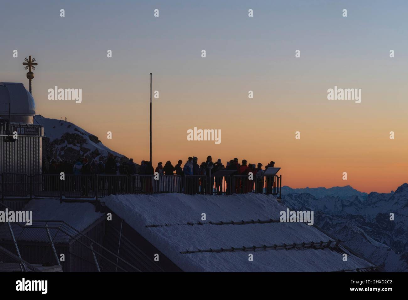 Morgenstimmung auf der Zugspitze, Sonnenaufgang auf Deutschlands höchstem Berg 'Top of Germany'. Landschaftsfotografie mit Zugspitzkreuz (4,88 m). Frühaufsteher warten, bis die Sonne aufgeht. Stockfoto