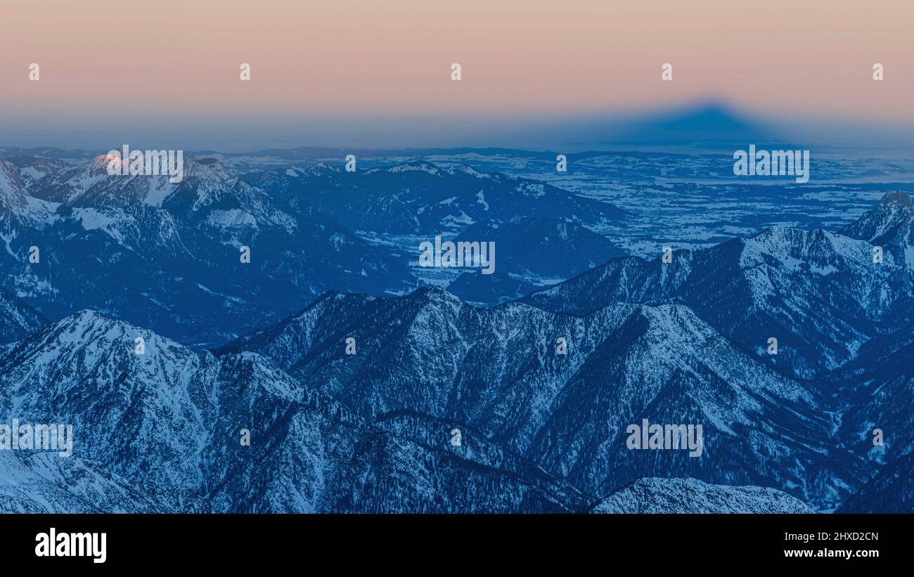 Morgenstimmung auf der Zugspitze, Sonnenaufgang auf Deutschlands höchstem Berg 'Top of Germany'. Landschaftsfotografie. Blick ins blaue Land, hohe Kiste sichtbar. Zugspitze wirft Schatten. Stockfoto