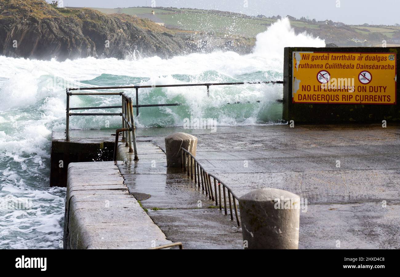 Sturmwellen brechen über die Sicherheitsbarriere der Handschiene Rosscarbery Pier, Irland. Stockfoto
