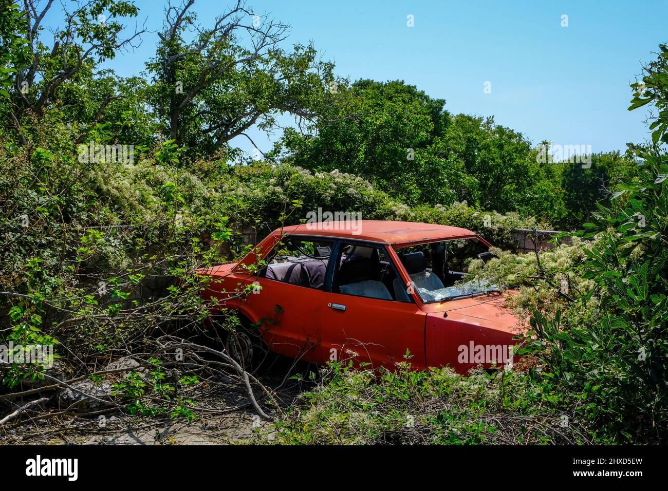 Theologos, Thassos, Griechenland - im Bergdorf Theologos auf der Insel Thassos steht in der Landschaft ein alter, rostroter Schrottwagen, der langsam von Pflanzen bewachsen wird. Stockfoto