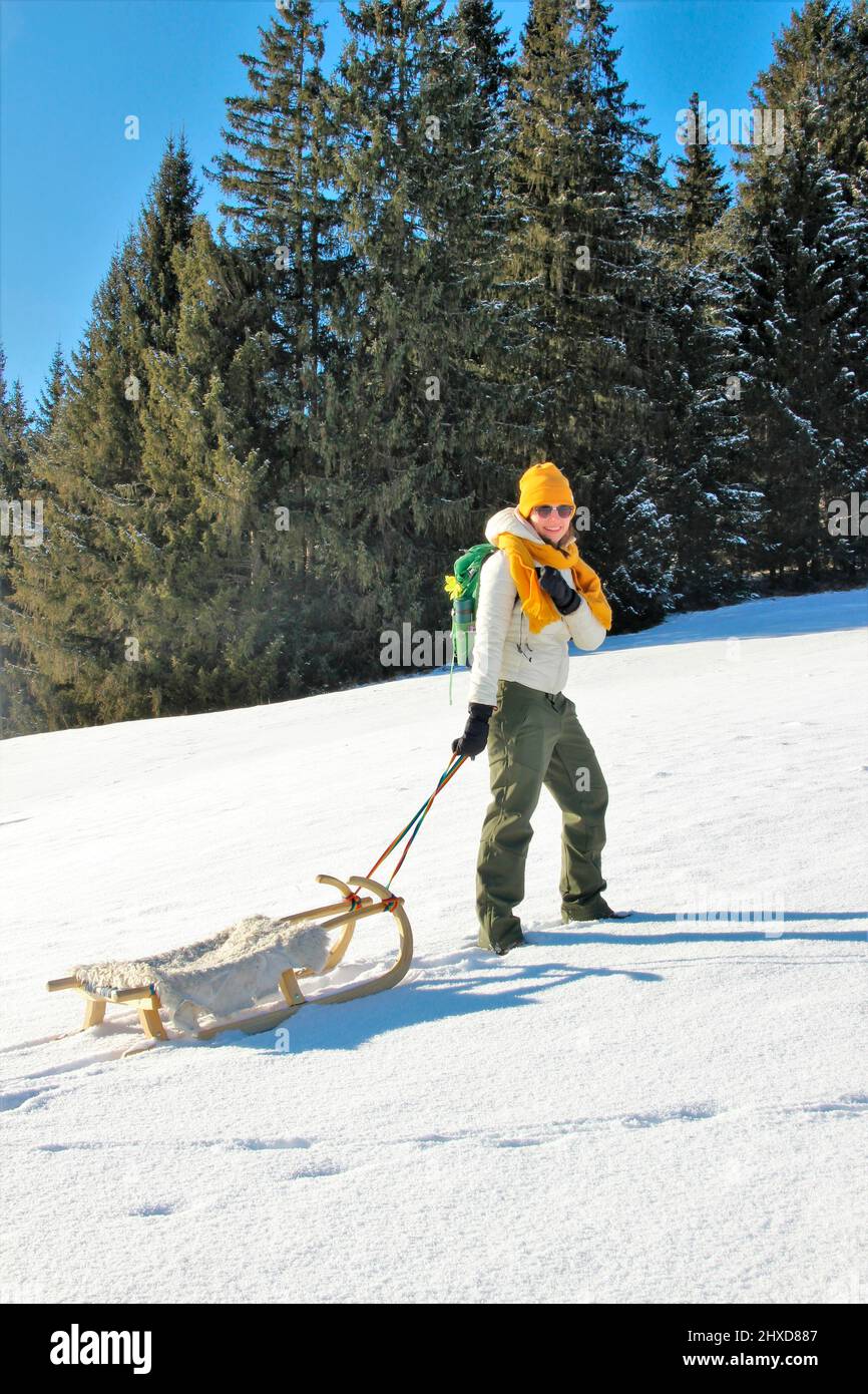 Junge Frau auf Winterwanderung bei Mittenwald, Schlitten vor Bergkulisse im Schnee, Bayern, Oberbayern, Deutschland, Urlaub, Winter, Stockfoto