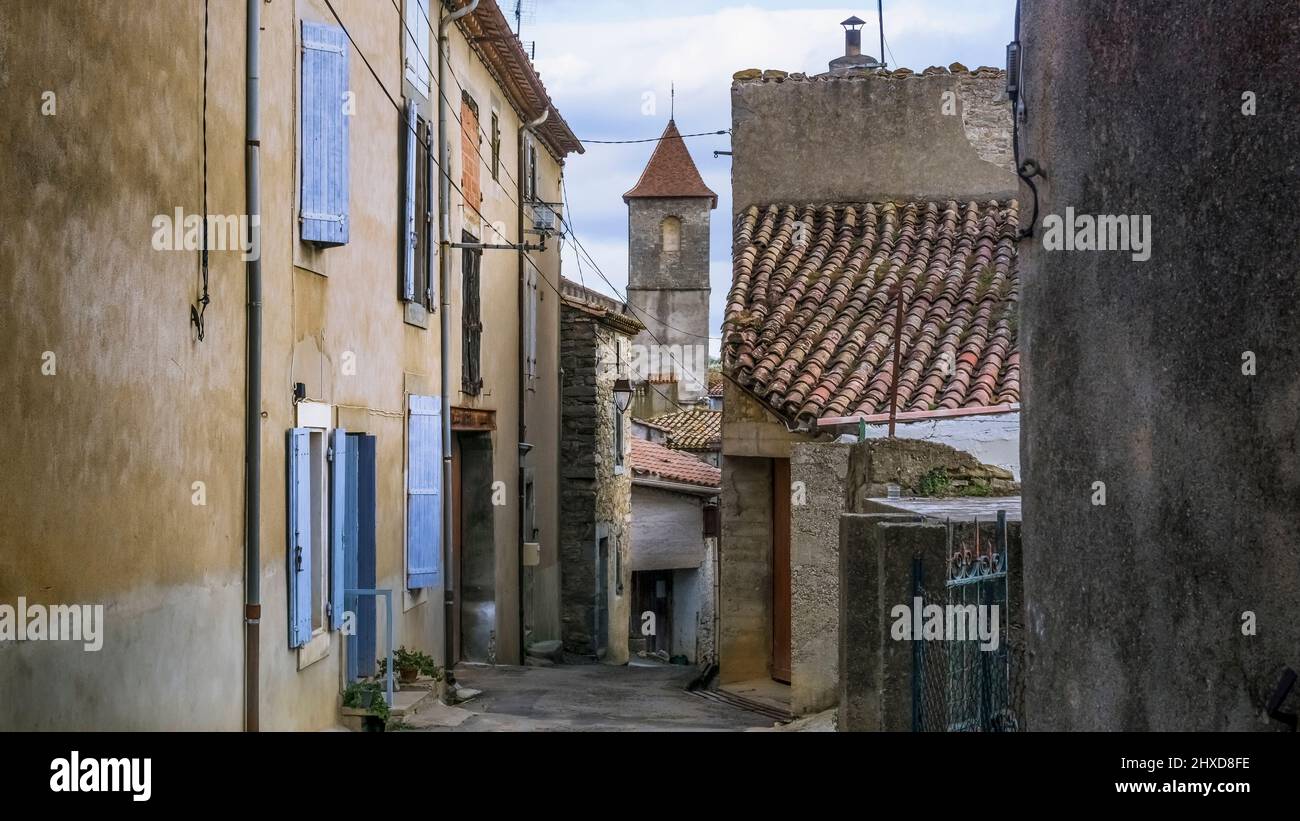 Dorfstraße in Azillanet mit Blick auf den Kirchturm Saint Laurent. Das Gemeindegebiet gehört zum Regionalen Naturpark Haut Languedoc. Stockfoto
