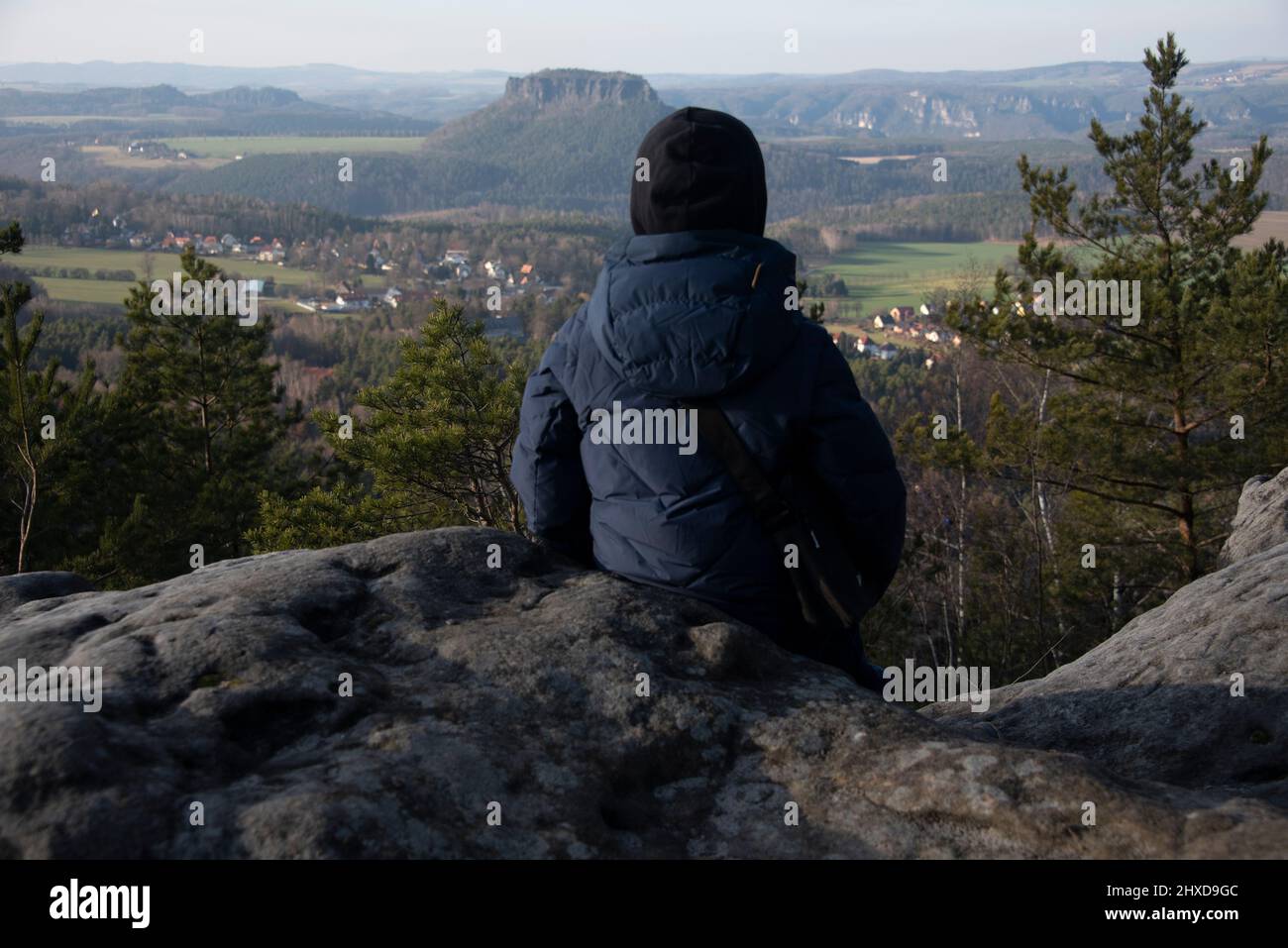 Ein Junge sitzt auf dem Papststein und blickt auf den Lilienstein, Tafelberg im Elbsandsteingebirge, gelegen am Malerweg, Papstdorf, Sachsen, Deutschland Stockfoto