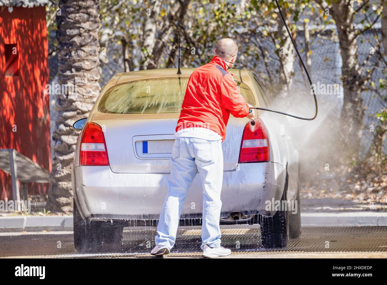 Ein nicht identifizierter Mann reinigt sein Auto mit einem Hochdruckwasser an der Tankstelle Stockfoto