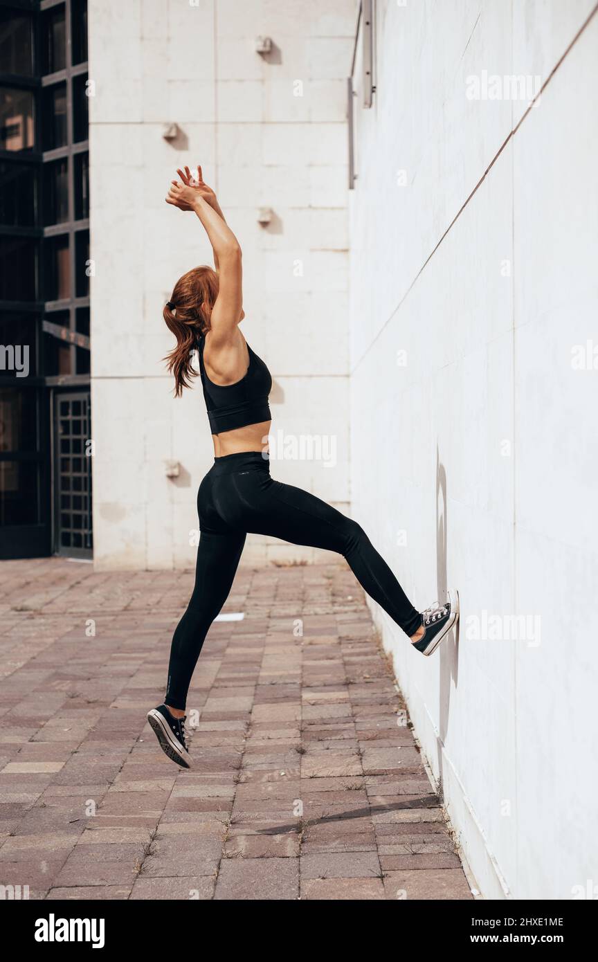 Junge Parkour und Freerunning Frauen machen einen Backflip von einer Wand im urbanen Hintergrund, springen taumelnde Gymnastik Trainingskonzept Stockfoto
