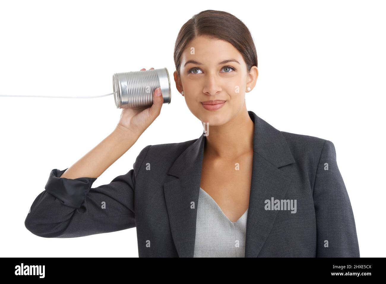 Kommunikation mit der alten Schule. Studioaufnahme einer attraktiven jungen Geschäftsfrau, die ihrem Blechdosen-Telefon zuhört. Stockfoto