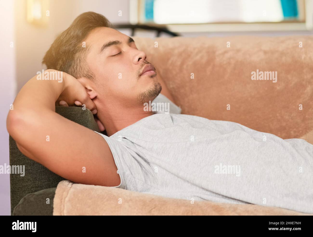 Vierzig Augenzwinkern auf der Couch fangen. Aufnahme eines jungen Mannes, der zu Hause auf seiner Couch schläft. Stockfoto