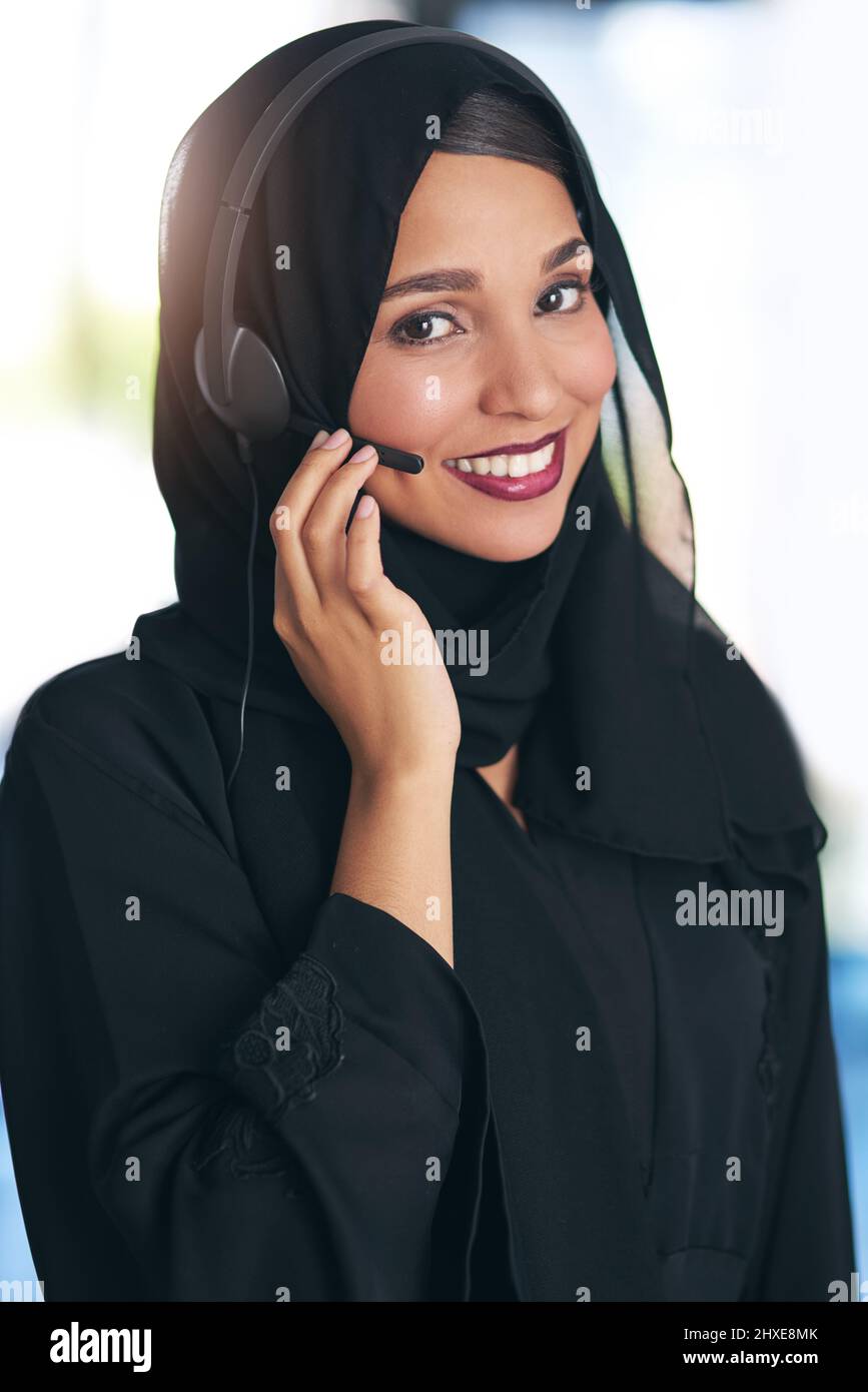 Hier können Sie Ihre Fragen beantworten. Porträt eines freundlichen jungen muslimischen Callcenters, der in einem modernen Büro arbeitet. Stockfoto