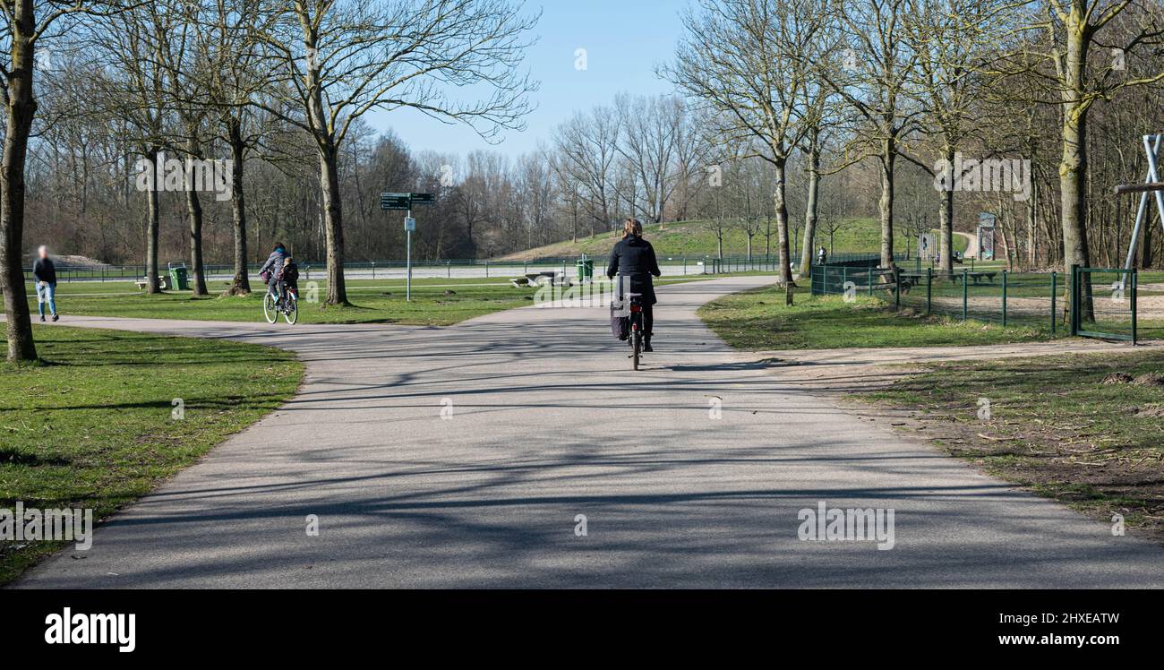 Nicht erkennbare Menschen radeln und genießen ihren Tag im Park namens Haarlemmermeerse bos in Hoofddorp in den Niederlanden Stockfoto