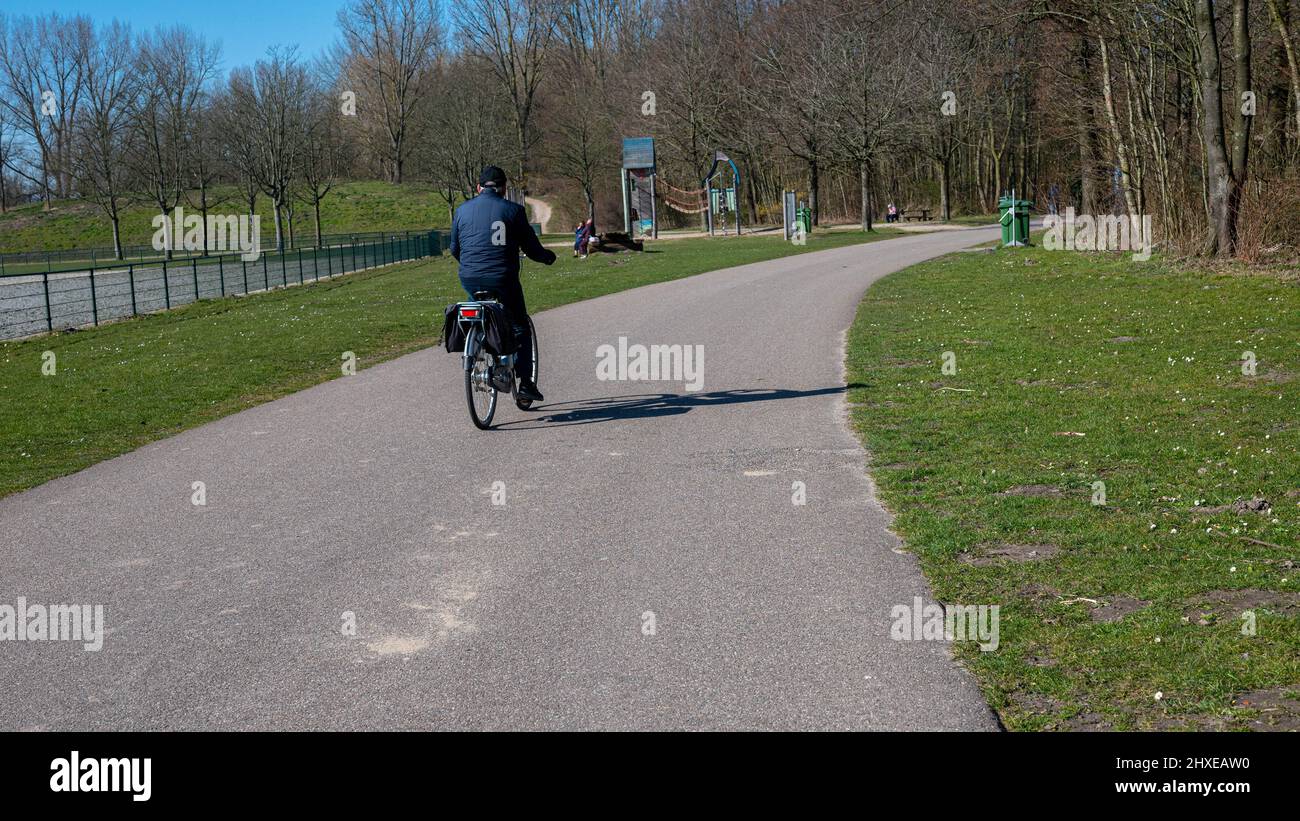 Nicht erkennbare Menschen radeln und genießen ihren Tag im Park namens Haarlemmermeerse bos in Hoofddorp in den Niederlanden Stockfoto