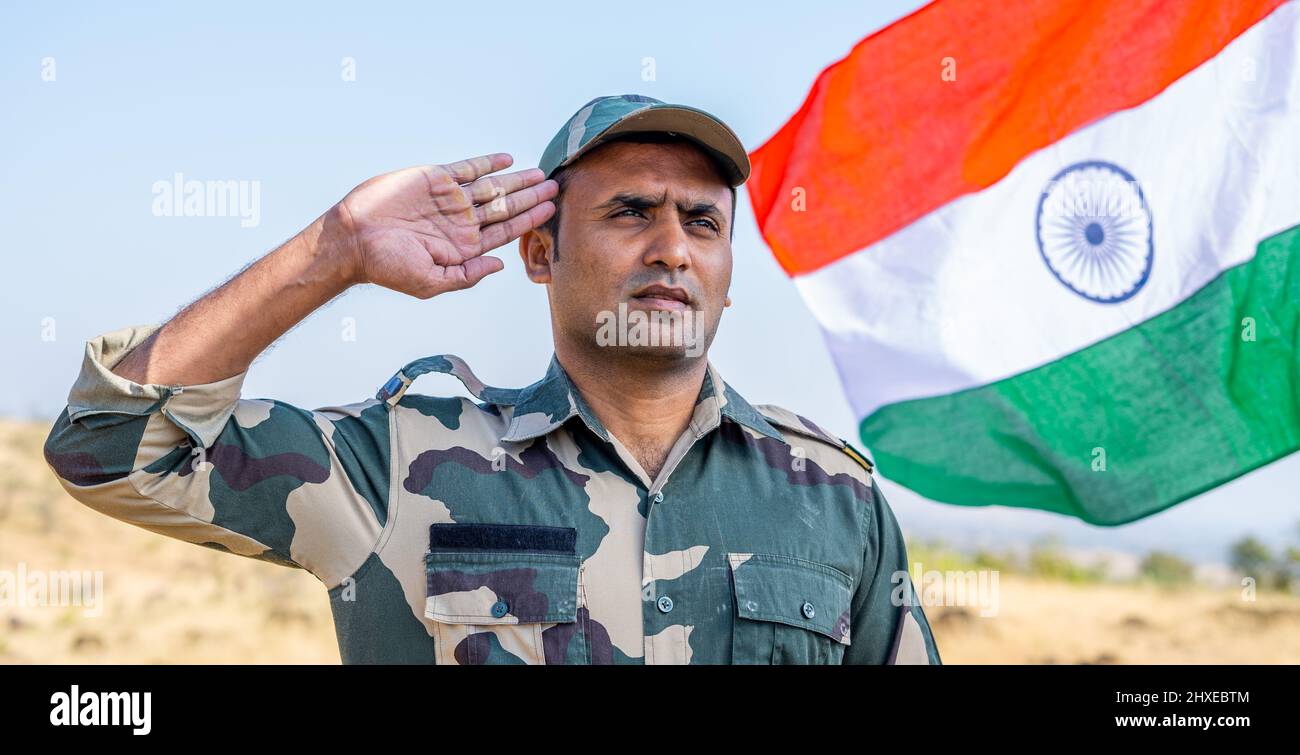 Frontansicht aus dem unteren Winkel des stolzen Soldaten der indischen Armee, der im Hintergrund die indische Flagge schwenkt - Konzept des patriotischen Nationalismus Stockfoto