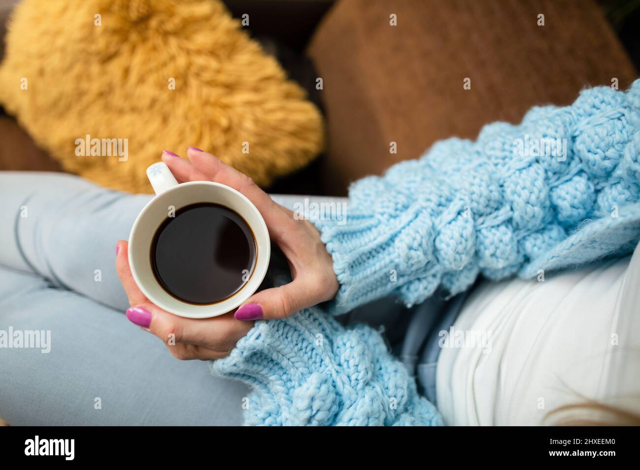 Eine Tasse heißen Kaffee in den Händen einer Frau zu Hause. Stockfoto