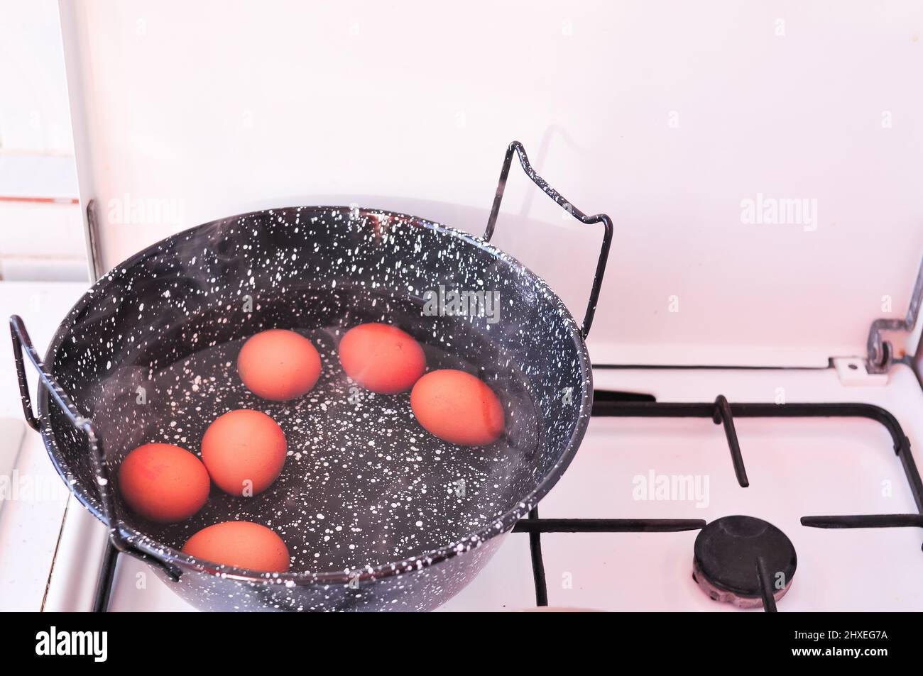 Eier in Schale in kochendem Wasser in schwarzem Topf auf dem Herd. Hochwertige Fotos Stockfoto