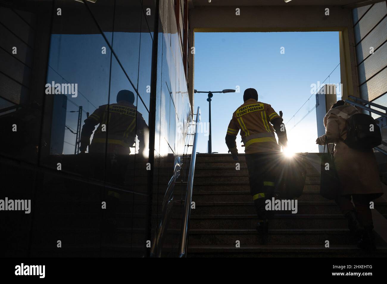 Przemysl, Polen. 12. März 2022. Eine Feuerwehrfrau hilft einem Flüchtling aus der Ukraine, ihren Koffer die Stufen hinauf zum Bahnsteig am Hauptbahnhof zu tragen. Am 24. Februar drangen russische Truppen in die Ukraine ein. Quelle: Sebastian Gollnow/dpa/Alamy Live News Stockfoto