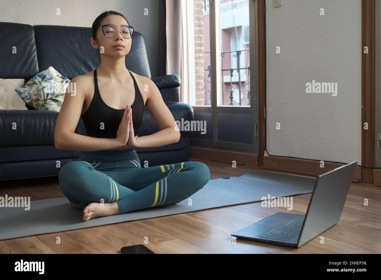 Junge asiatische Frau hört entspannende Musik und meditiert dabei die einfache Pose. Stockfoto