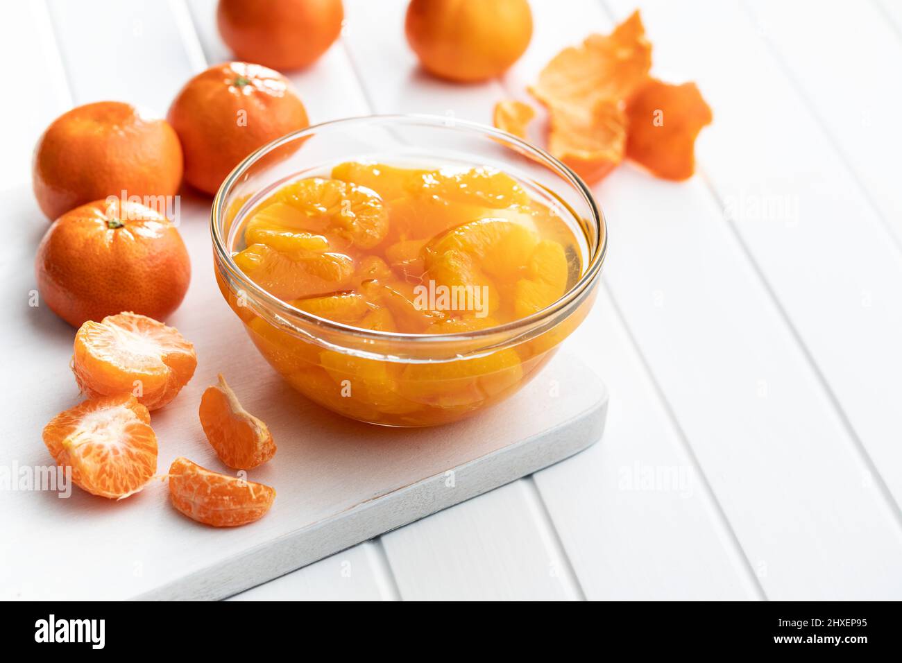 Mandarine aus der Dose. Eingelegte Mandarinenfrucht in der Schüssel auf weißem Tisch. Stockfoto