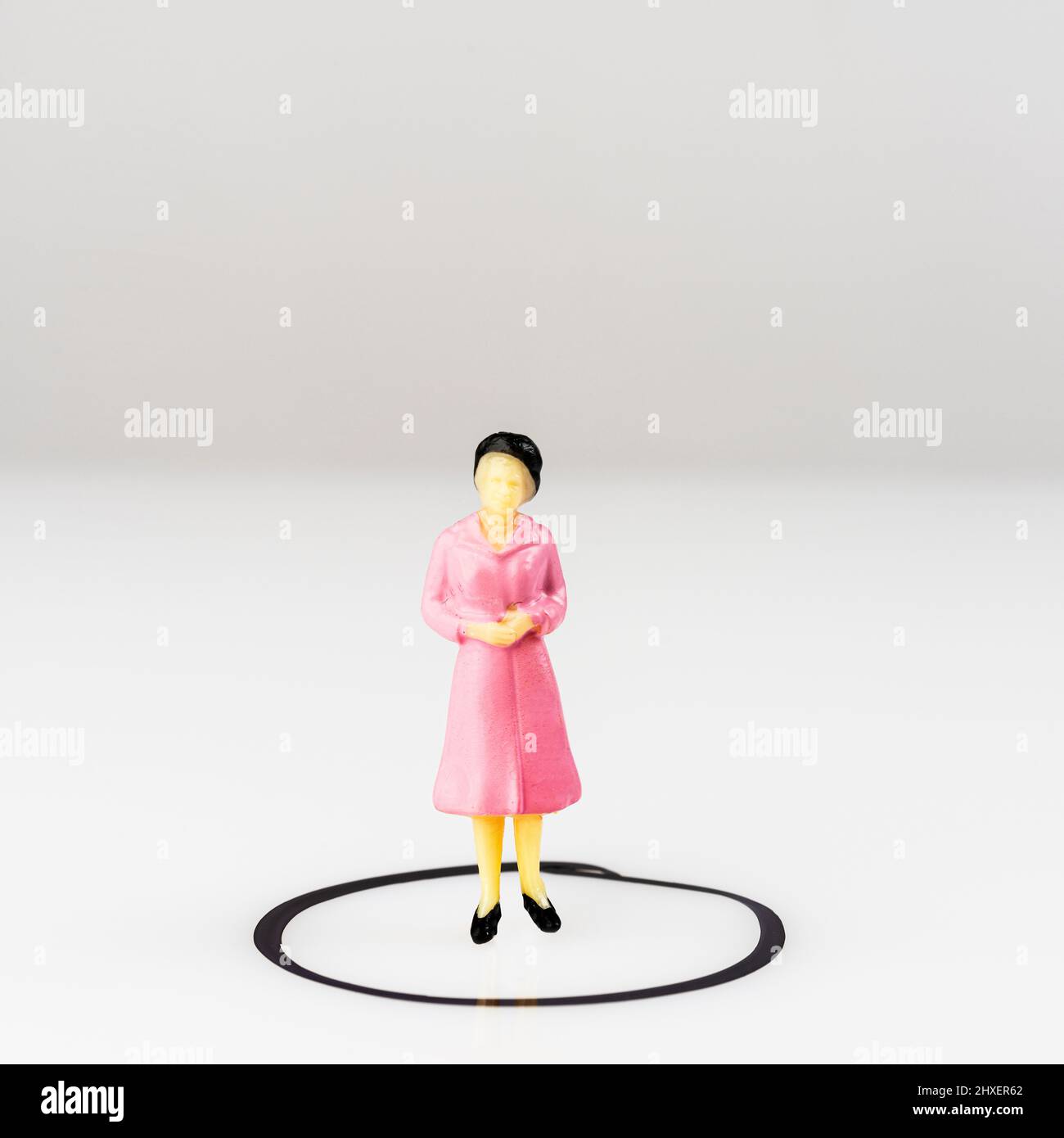 Ein Miniaturmodell einer Frau, isoliert in einem Kreis, der auf einer Oberfläche gezeichnet ist Stockfoto