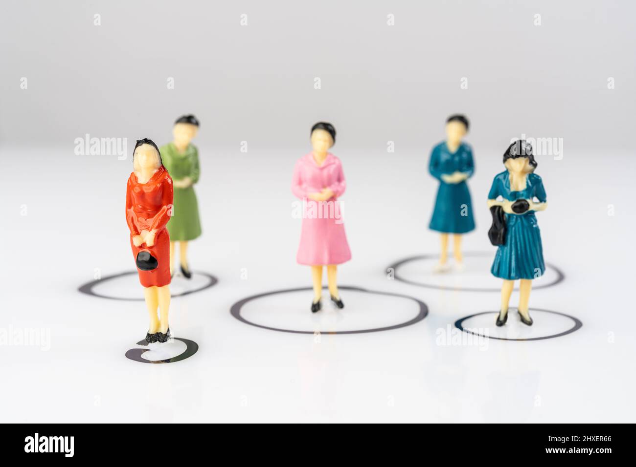 Einzelne Miniatur-weibliche Modelle isoliert in Kreisen auf einer weißen Oberfläche gezeichnet Stockfoto