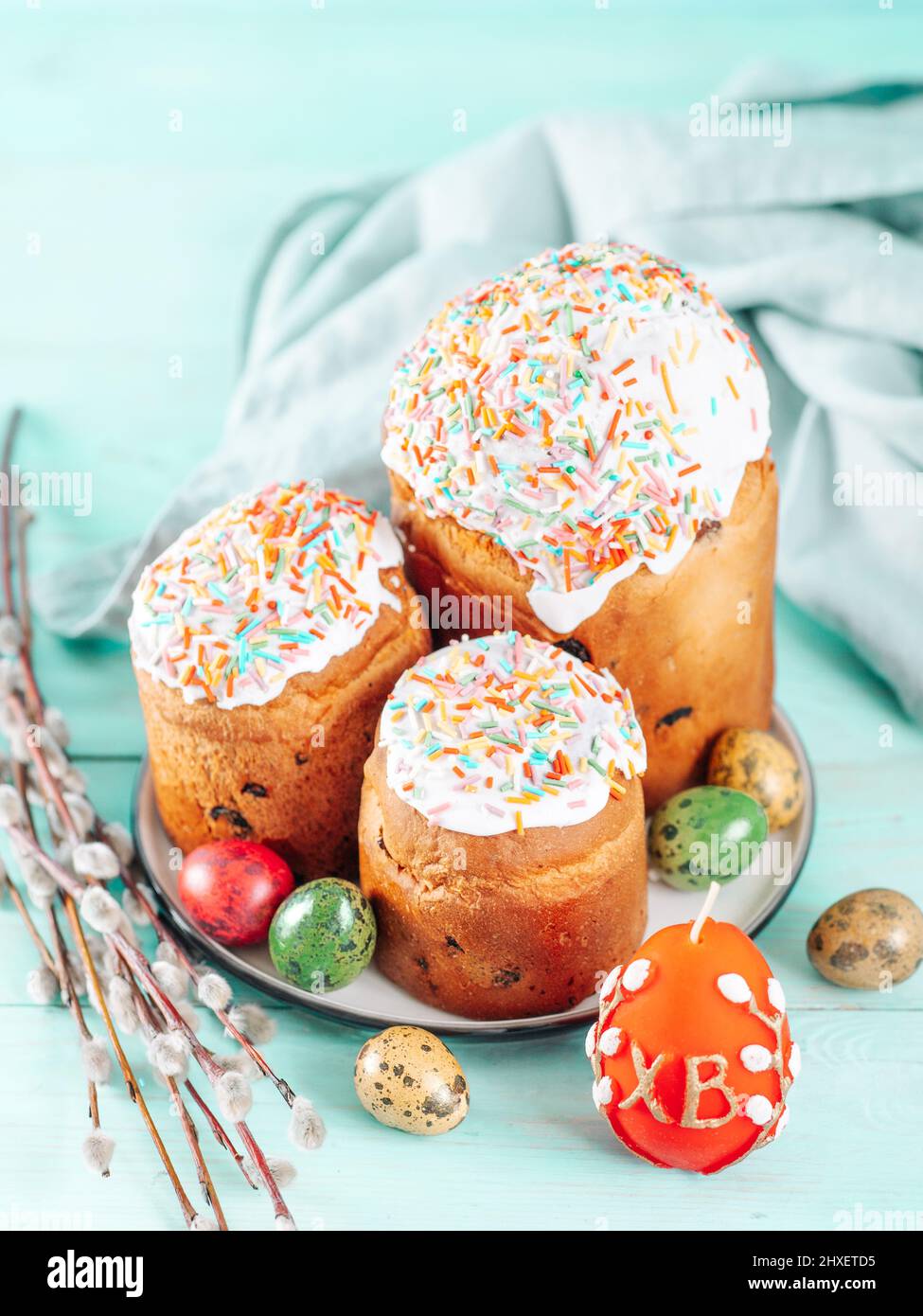 Traditionelle Russische Ukrainische Osterkuchen Kulich. Orthodox-christliches Osterbrot oder Osterkuchen mit Frosting, Ostereiern und Weidenzweigen auf blauem Hintergrund. Platz für Text kopieren, vertikal Stockfoto