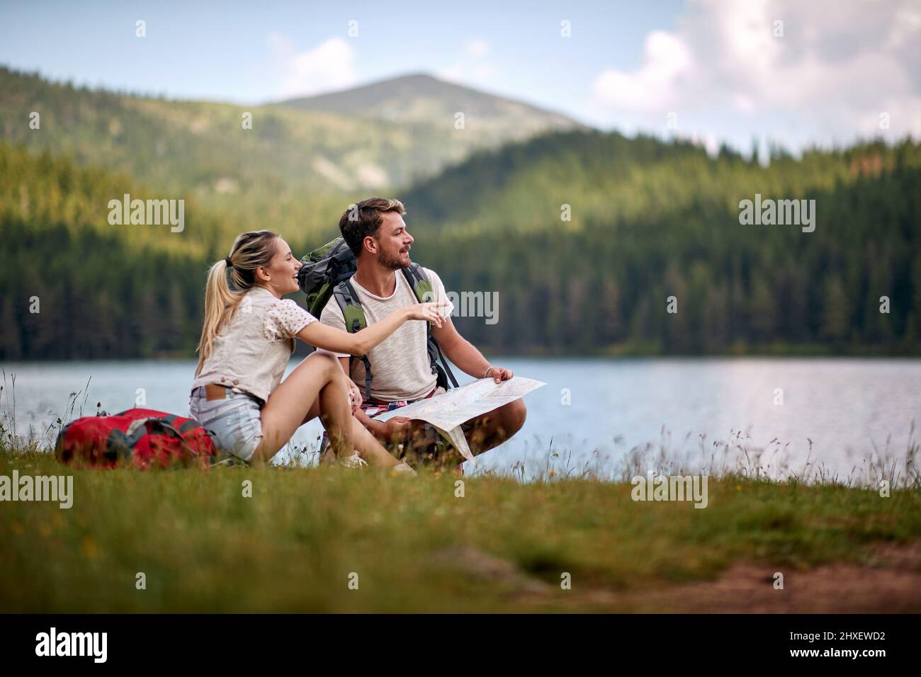 Touristenpaar mit Karte mit Blick auf den See. Sommerurlaub in der Natur. Lifestyle, Zweisamkeit, Naturkonzept Stockfoto