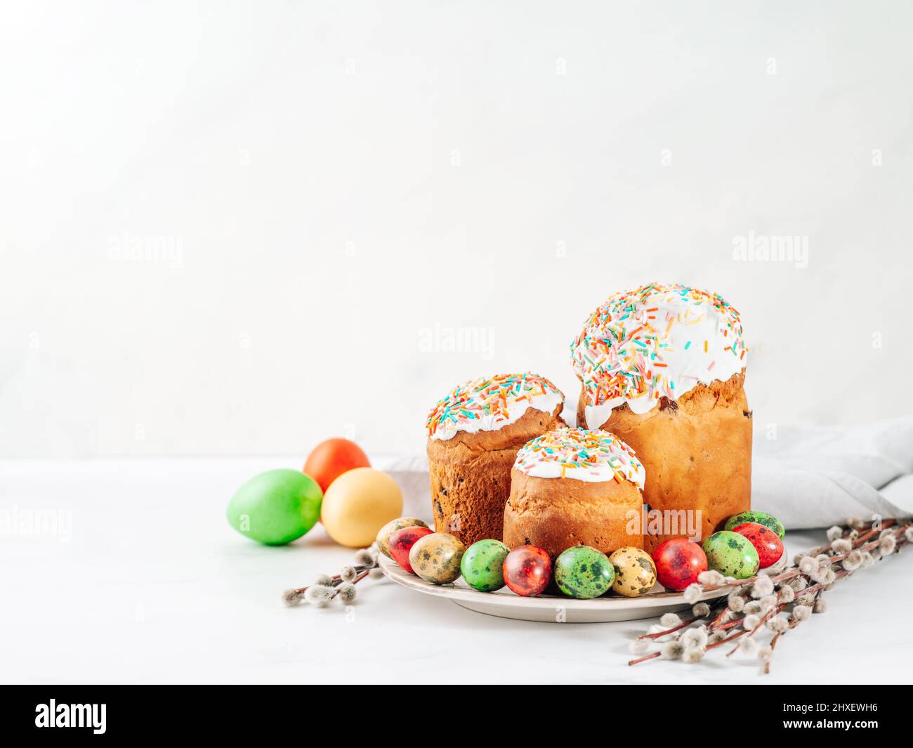 Traditionelle Russische Ukrainische Osterkuchen Kulich. Orthodoxes christliches Osterbrot oder Osterkuchen mit Frosting, Ostereiern und Weidenzweigen auf weißem Marmorhintergrund. Platz für Text oder Design kopieren Stockfoto