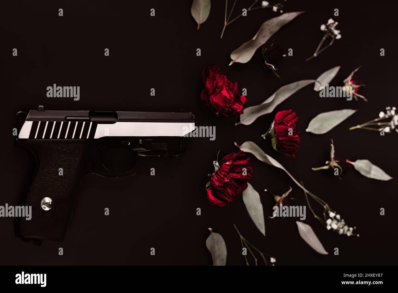 Flach legen für die Welt, auf einem schwarzen Hintergrund Pistole und Rosenblumen, Simulation eines Schusses Stockfoto