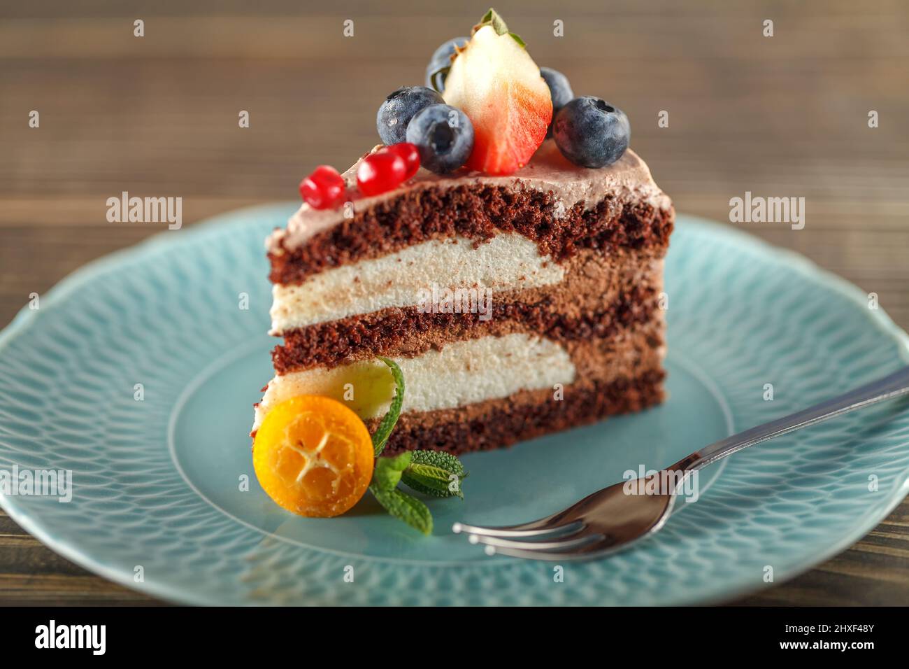 Schokoladenkuchen mit Haferkleie und Mandelmehl, garniert mit Heidelbeeren, Granatapfelkernen, Erdbeeren und frischen Minzblättern. Schokoladenkre Stockfoto
