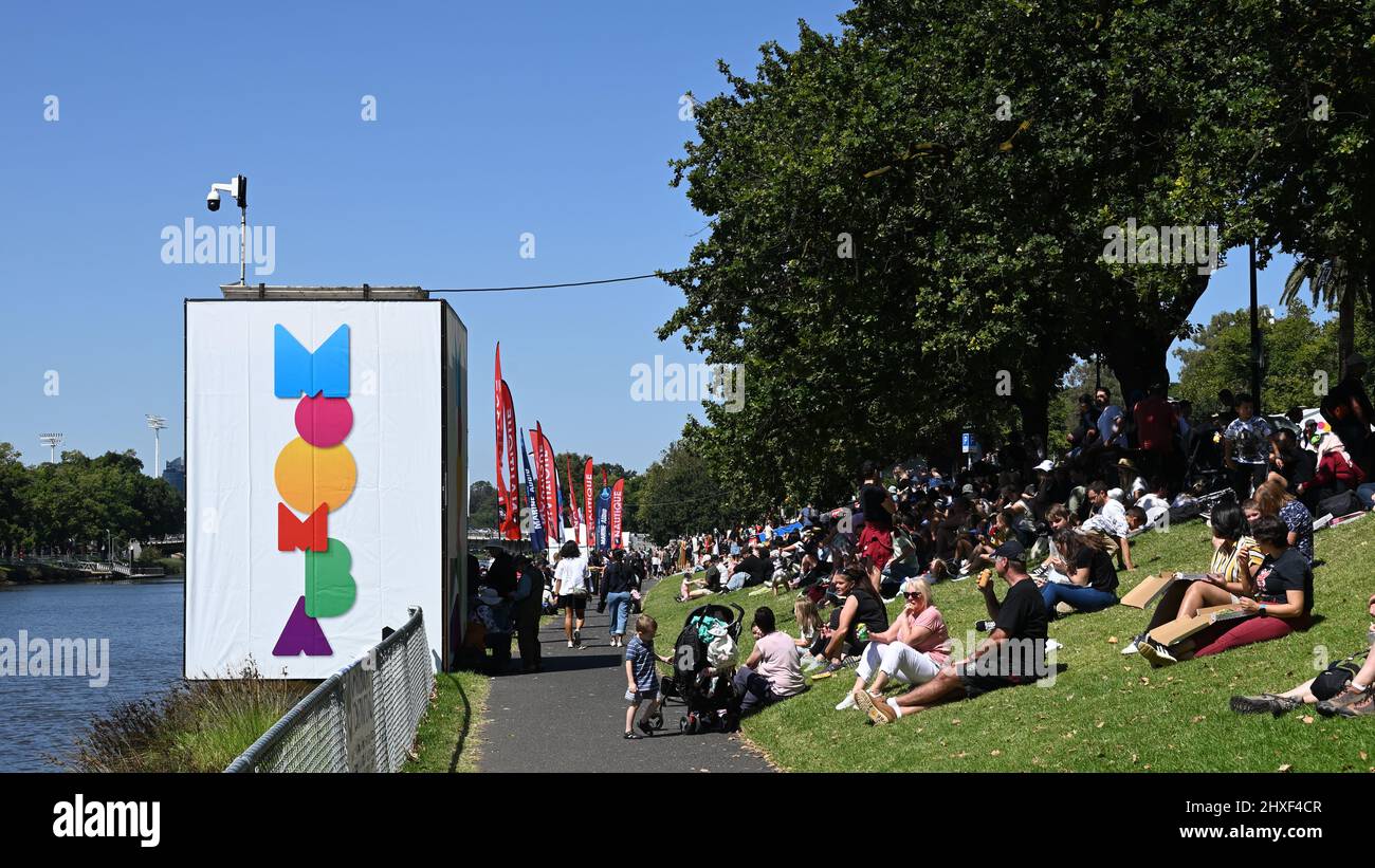 Massen von Menschen, die während des Moomba Festivals am südlichen Ufer des Yarra River sitzen und auf den Beginn eines Moomba Masters Events warten Stockfoto