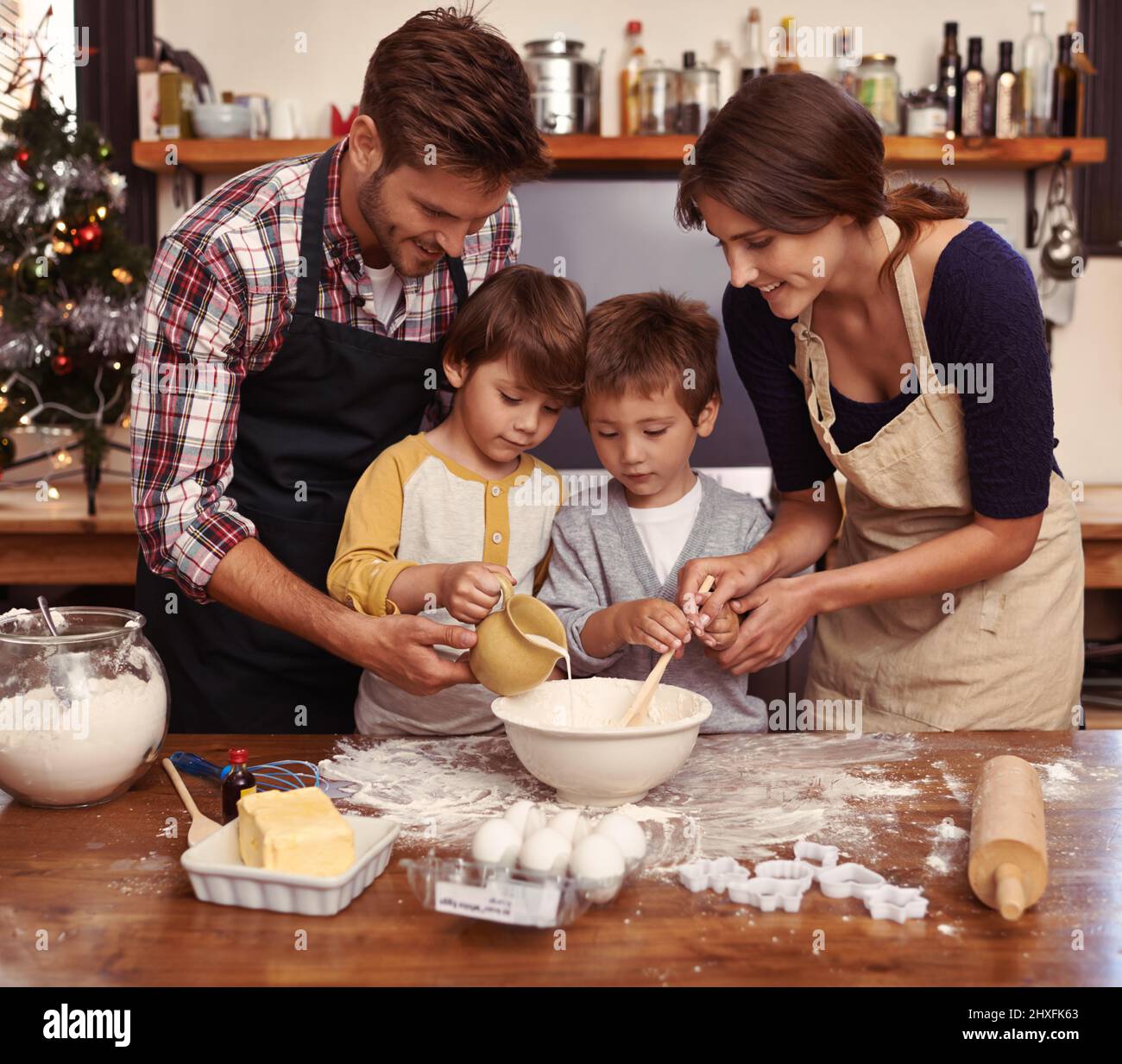 Süßes als Familie machen. Zwei niedliche kleine Jungen backen mit ihren Eltern in der Küche. Stockfoto