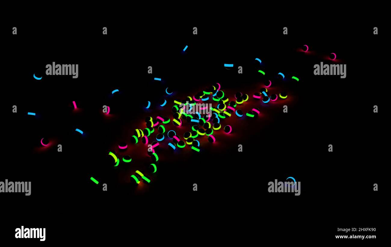Bunt leuchtende Kugeln fallen und Rollen auf schwarzem Hintergrund. Design. Viele schwarze Kinder spielen Kugeln mit Neonlichtern, die auf den Boden fallen. Stockfoto