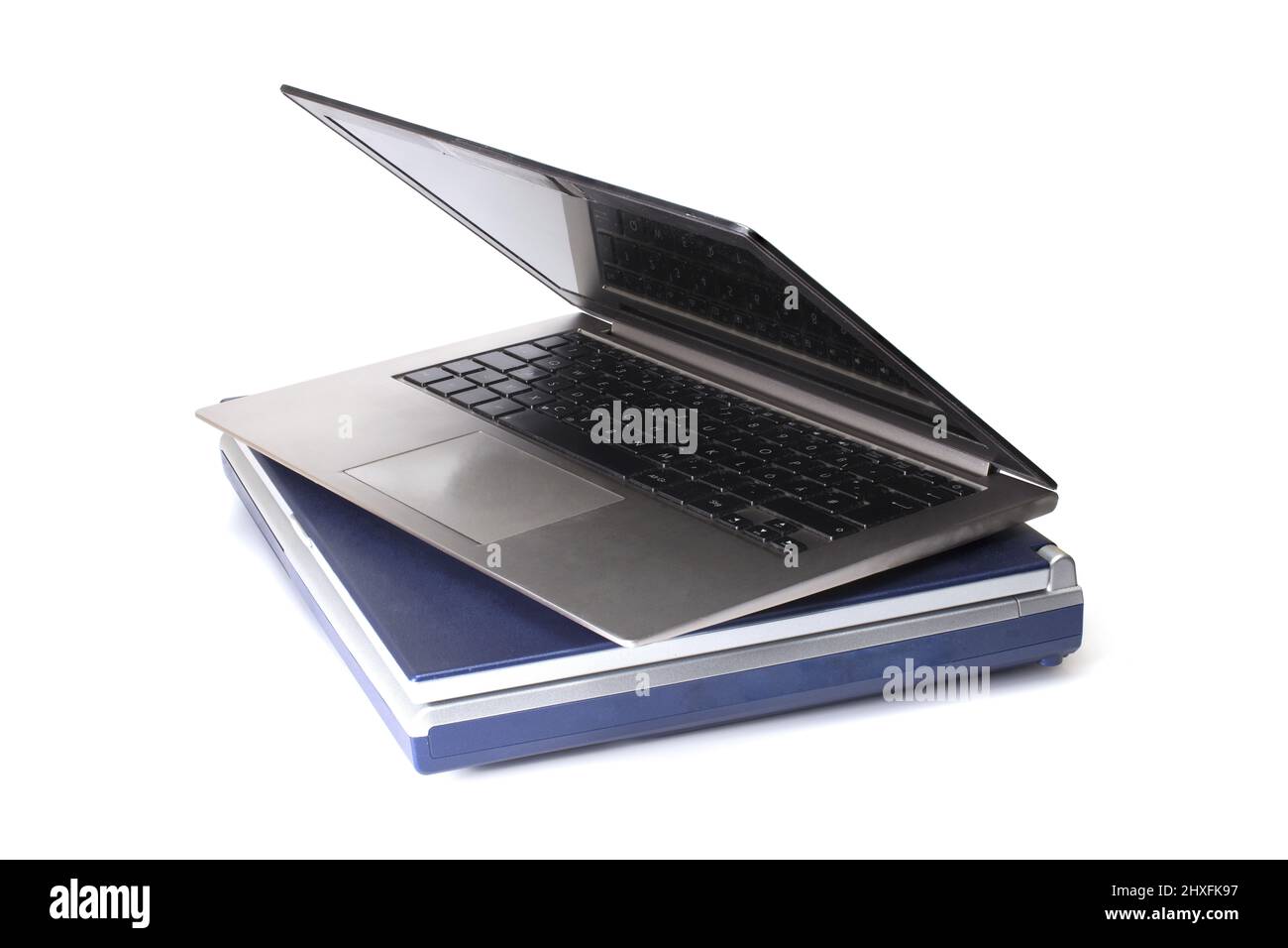 Nahaufnahme eines modernen Laptops auf einem alten schweren Notebook verschiedener Generationen von alt und schwer bis modern und ultraleicht auf weißem Hintergrund Konzept gestapelt Stockfoto