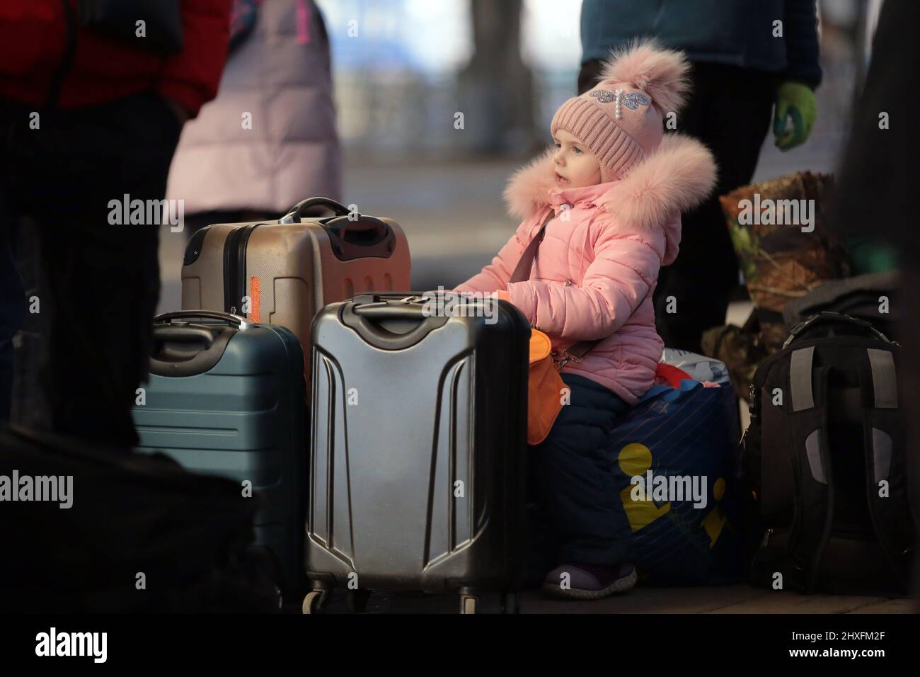 LVIV, UKRAINE - 11. MÄRZ 2022 - Ein kleines Mädchen sitzt an Koffern, während Menschen, die vor der russischen Invasion fliehen, auf einen Evakuierungszug nach Przemysl, Polen, warten. Stockfoto