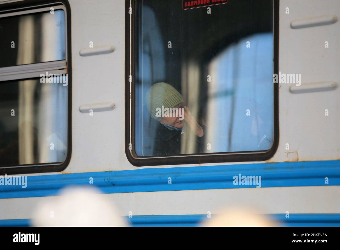 LVIV, UKRAINE - 11. MÄRZ 2022 - Eine ältere Frau wird in einem Fenster eines Wagens gesehen, während Menschen, die vor der russischen Invasion fliehen, auf einen Evakuierungszug warten Stockfoto