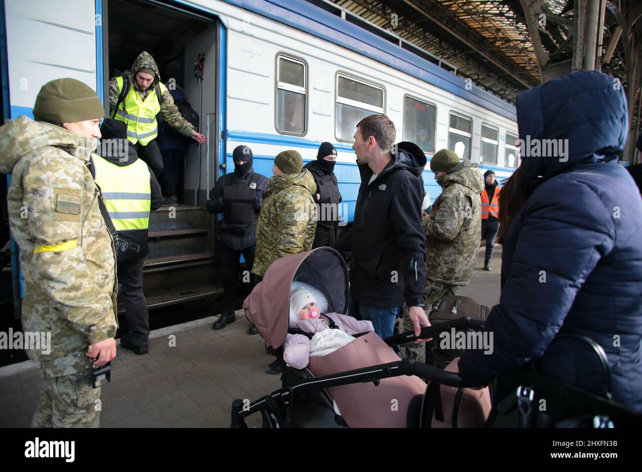 LVIV, UKRAINE - 11. MÄRZ 2022 - Eine Frau mit einem Baby im Kinderwagen steht auf der Plattform, während Menschen, die vor der russischen Invasion fliehen, auf einen Evakuierungszug warten Stockfoto