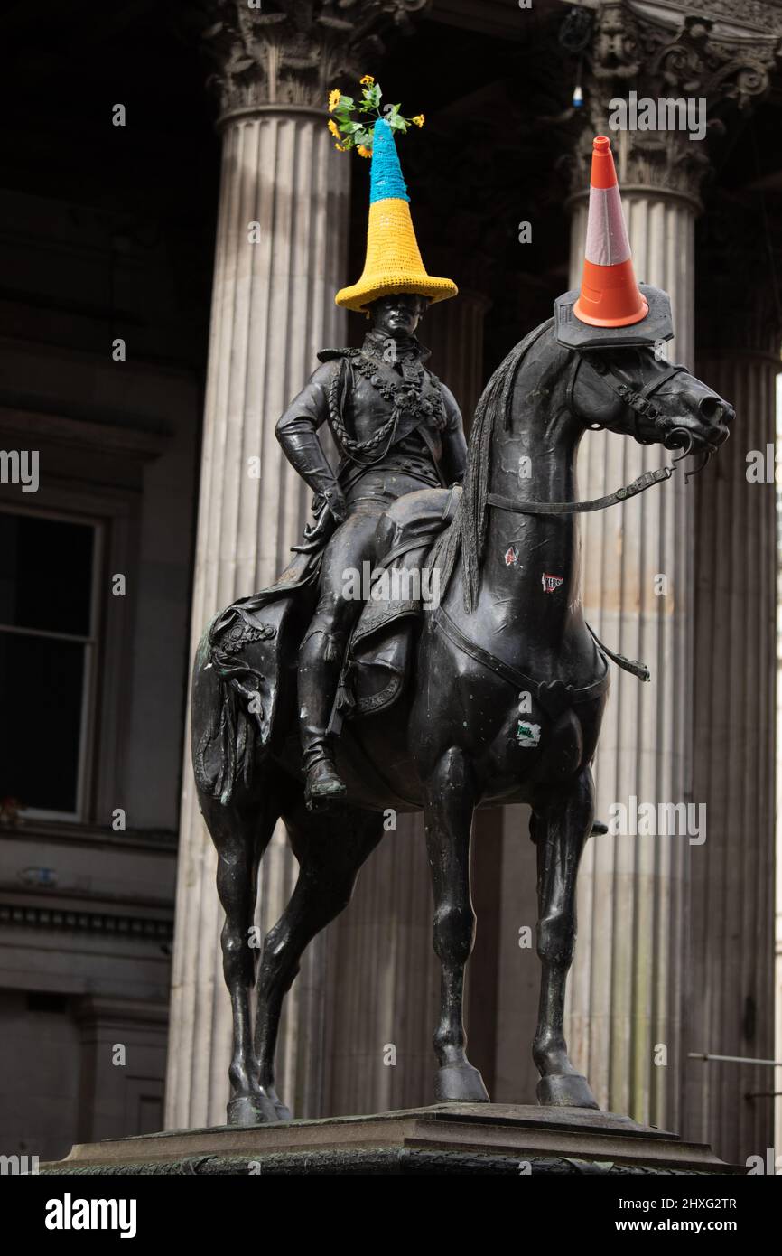 Glasgow, Großbritannien, 12.. März 2022. Die Statue des Herzogs von Wellington in der Queen Street trägt einen blau-gelben Polizeikegelhut mit ukrainischer Flagge, wie von Pauline McWhirter gehäkelt, zur Unterstützung der Ukraine in ihrem aktuellen Krieg mit Präsident PutinÕs Russia, in Glasgow, Schottland, 12. März 2022. Foto: Jeremy Sutton-Hibbert/Alamy Live News. Stockfoto