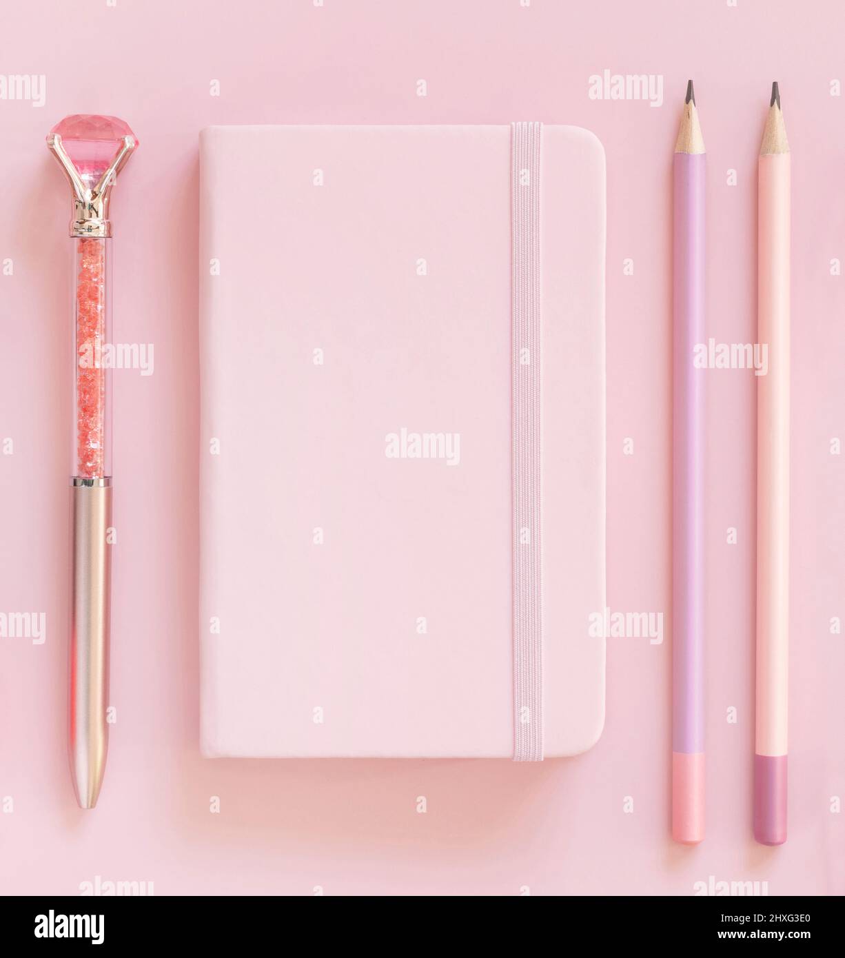 Pinkes Notizbuch, Pensils und dekorativer Edelsteinschreiber auf hellrosa Draufsicht. Textbuch-Modell, Planercover mit Platztext. Pädagogisch und girly c Stockfoto