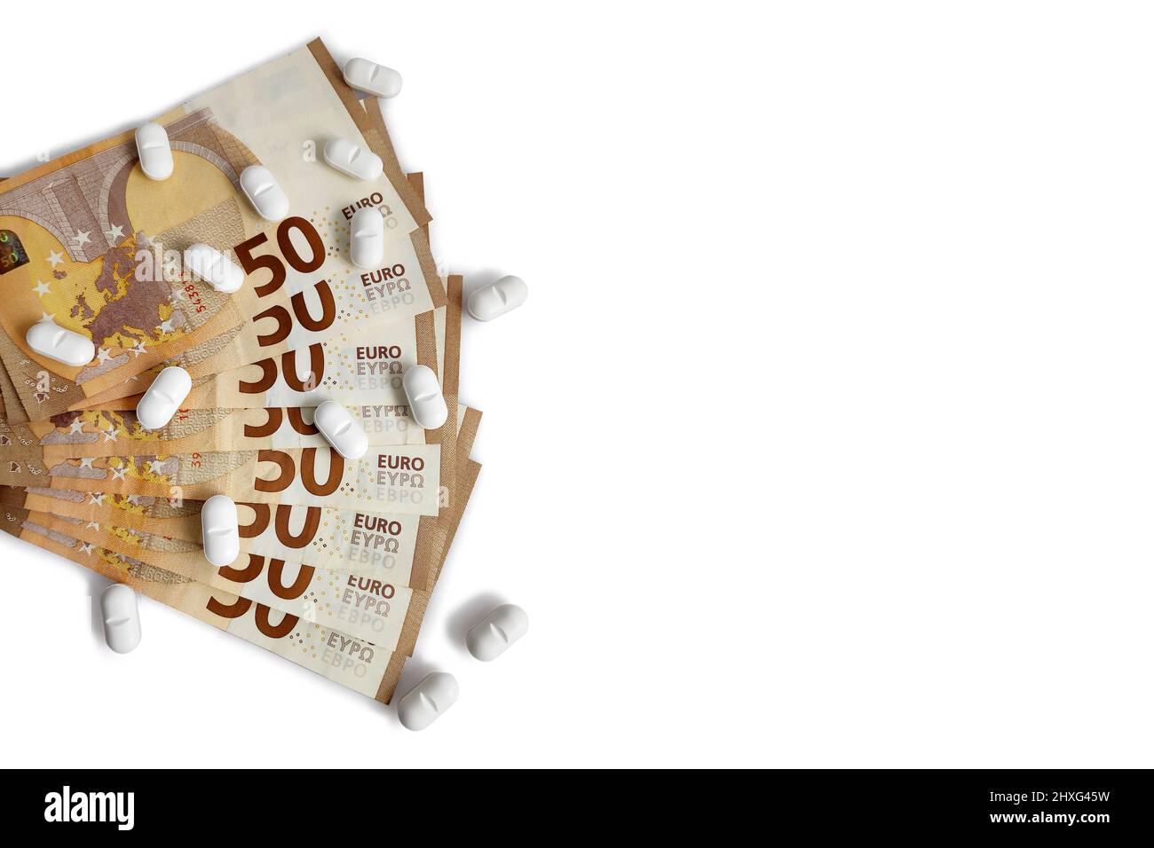 Verstreute pharmazeutische Pillen auf Euro-Banknoten isoliert auf weißem Hintergrund mit Kopieplatz. Stockfoto