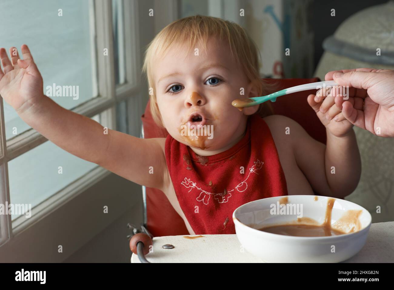 Wachsender Junge braucht sein Essen. Ein kleiner Junge, der in seinem Hochstuhl nach Herzenslust isst. Stockfoto